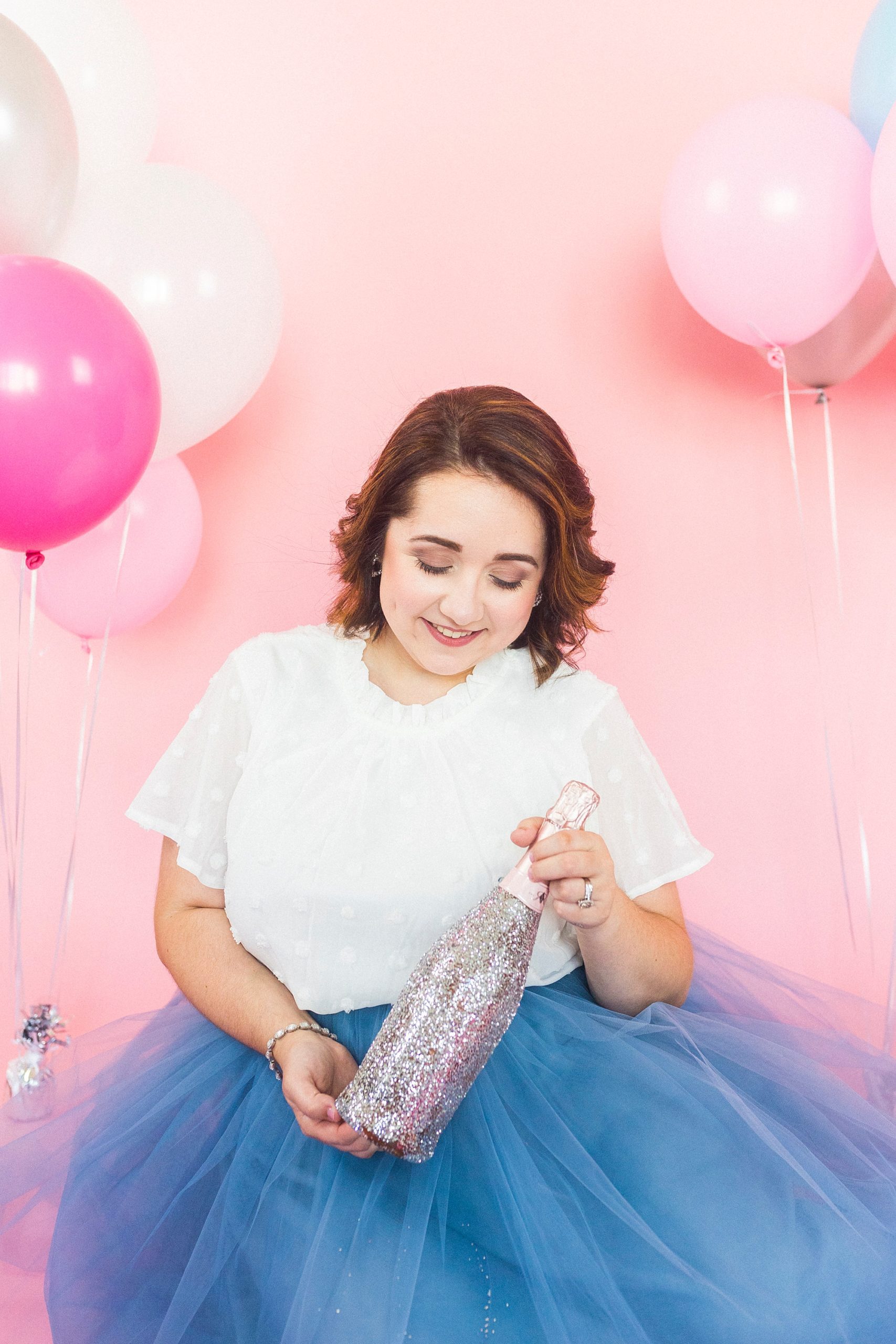 woman holds bottle of champagne during birthday photos