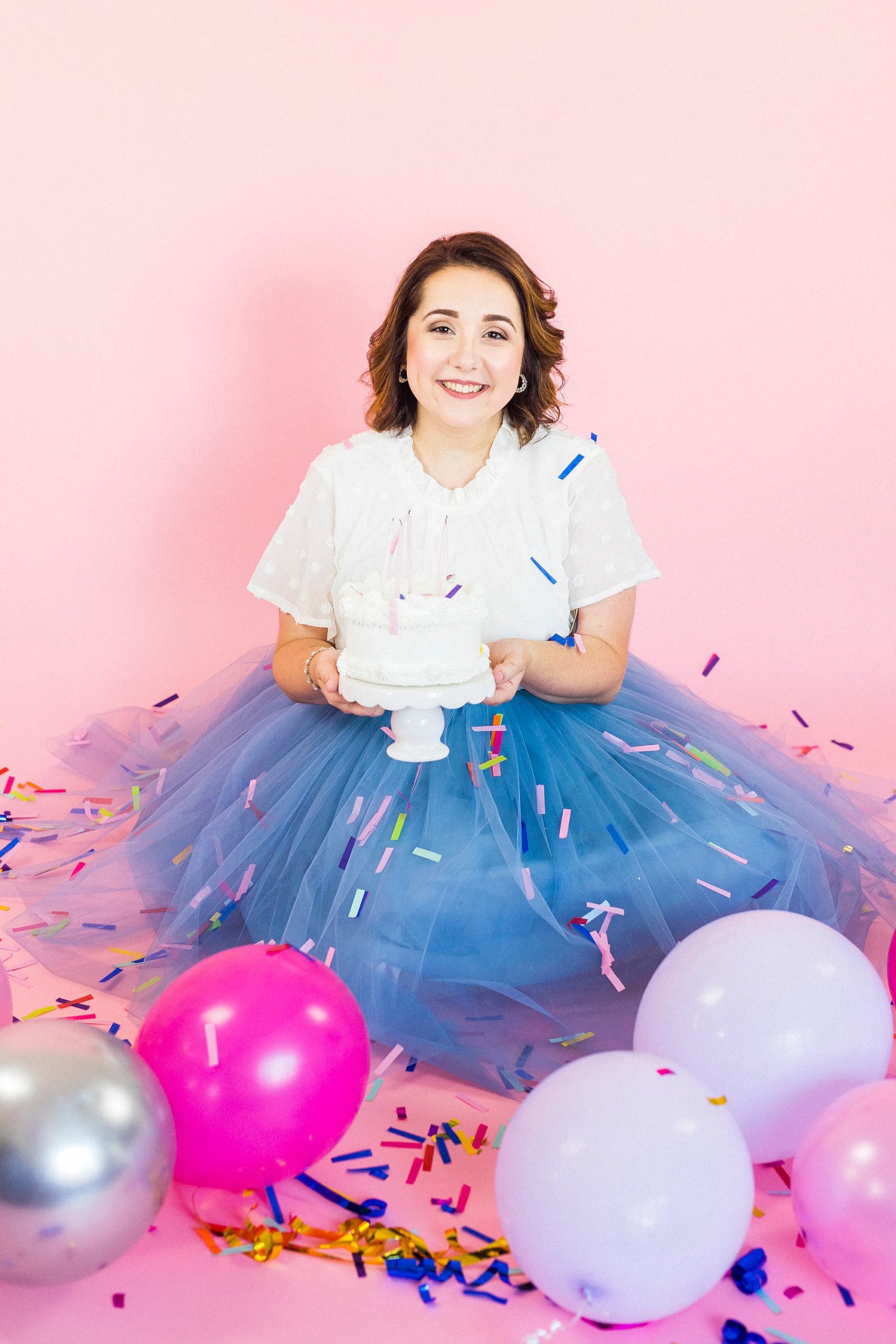 woman sits with white cake during 30th birthday portraits