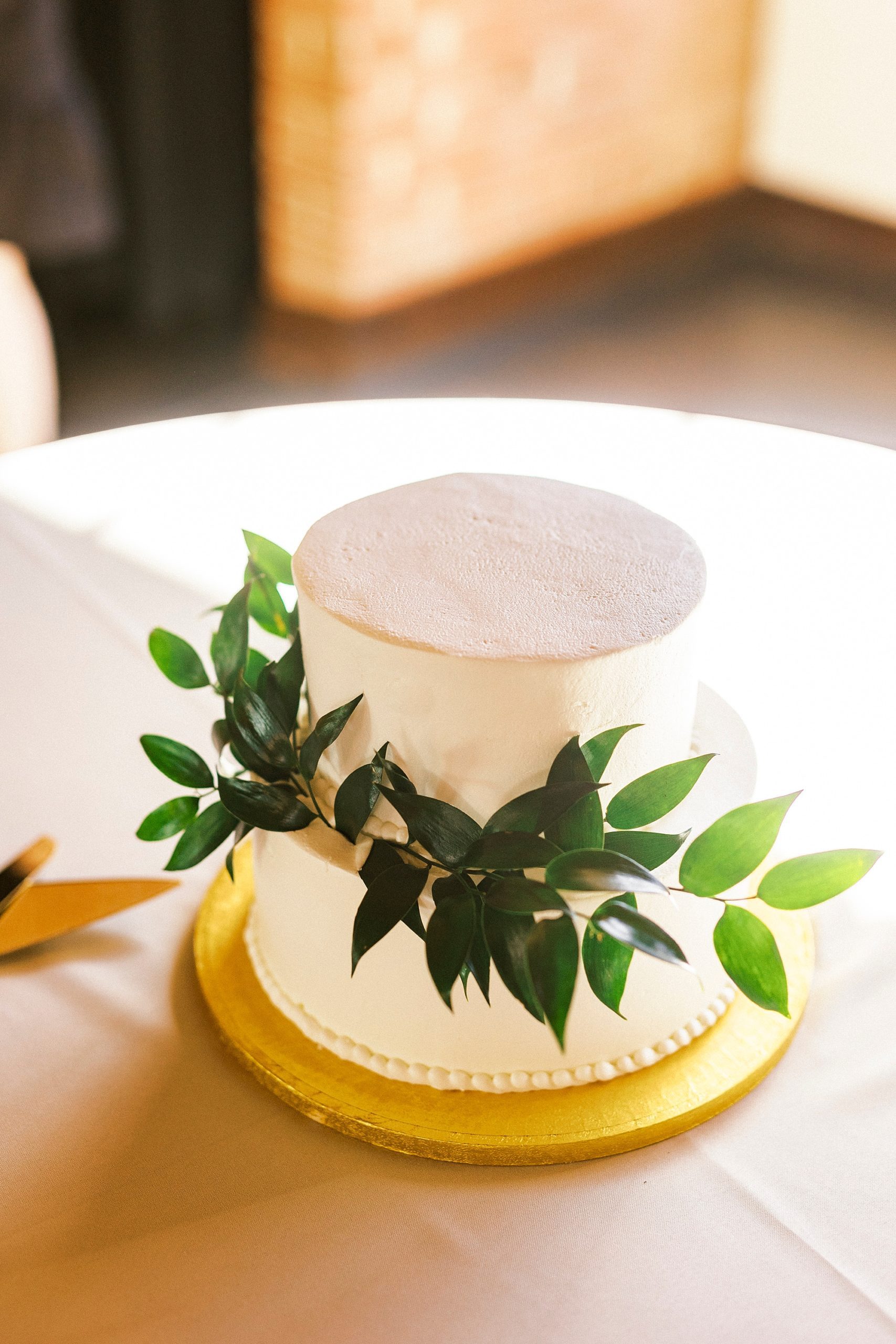 two-tiered wedding cake with greenery at Byron's South End