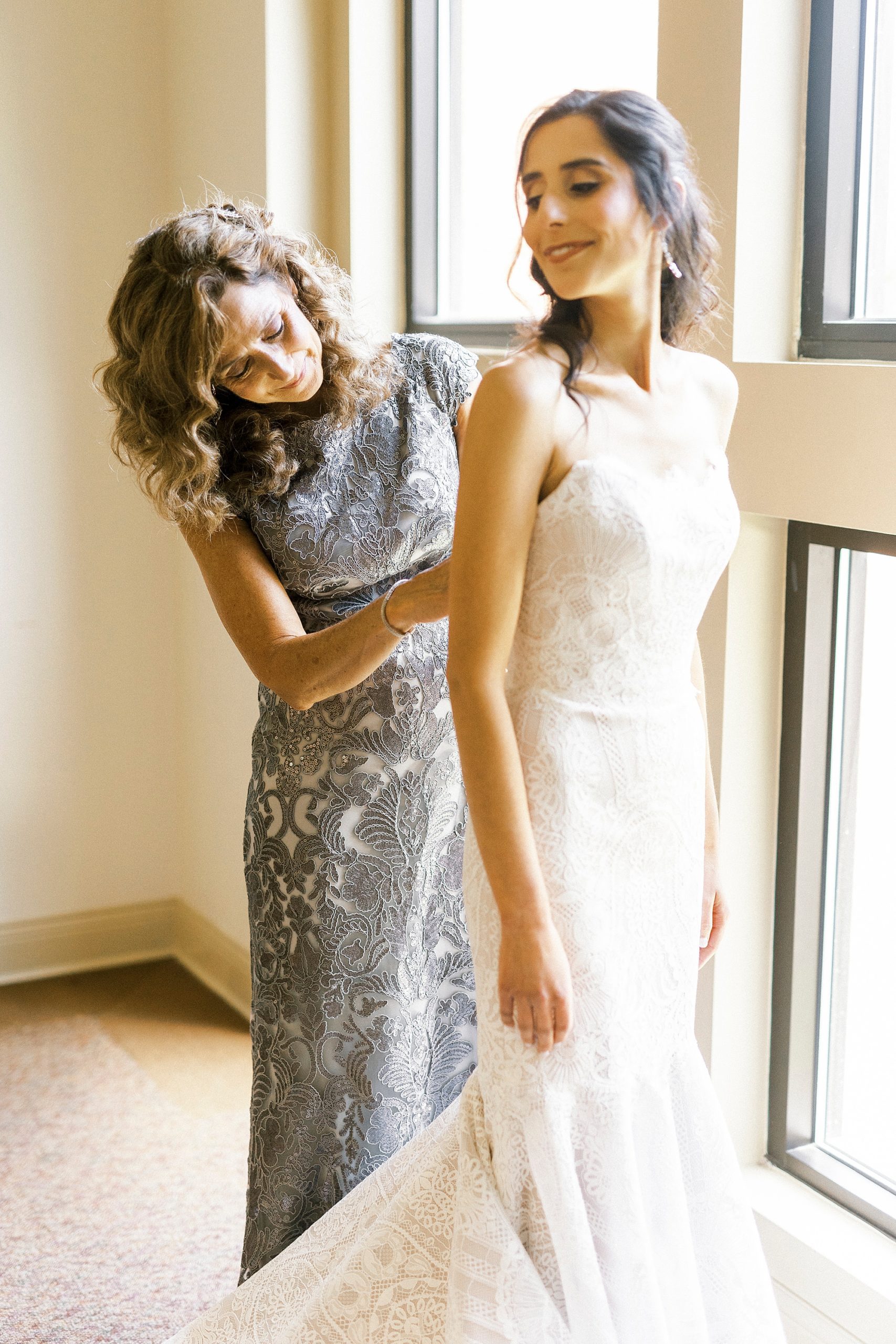 mother helps bride into wedding dress before Charlotte wedding