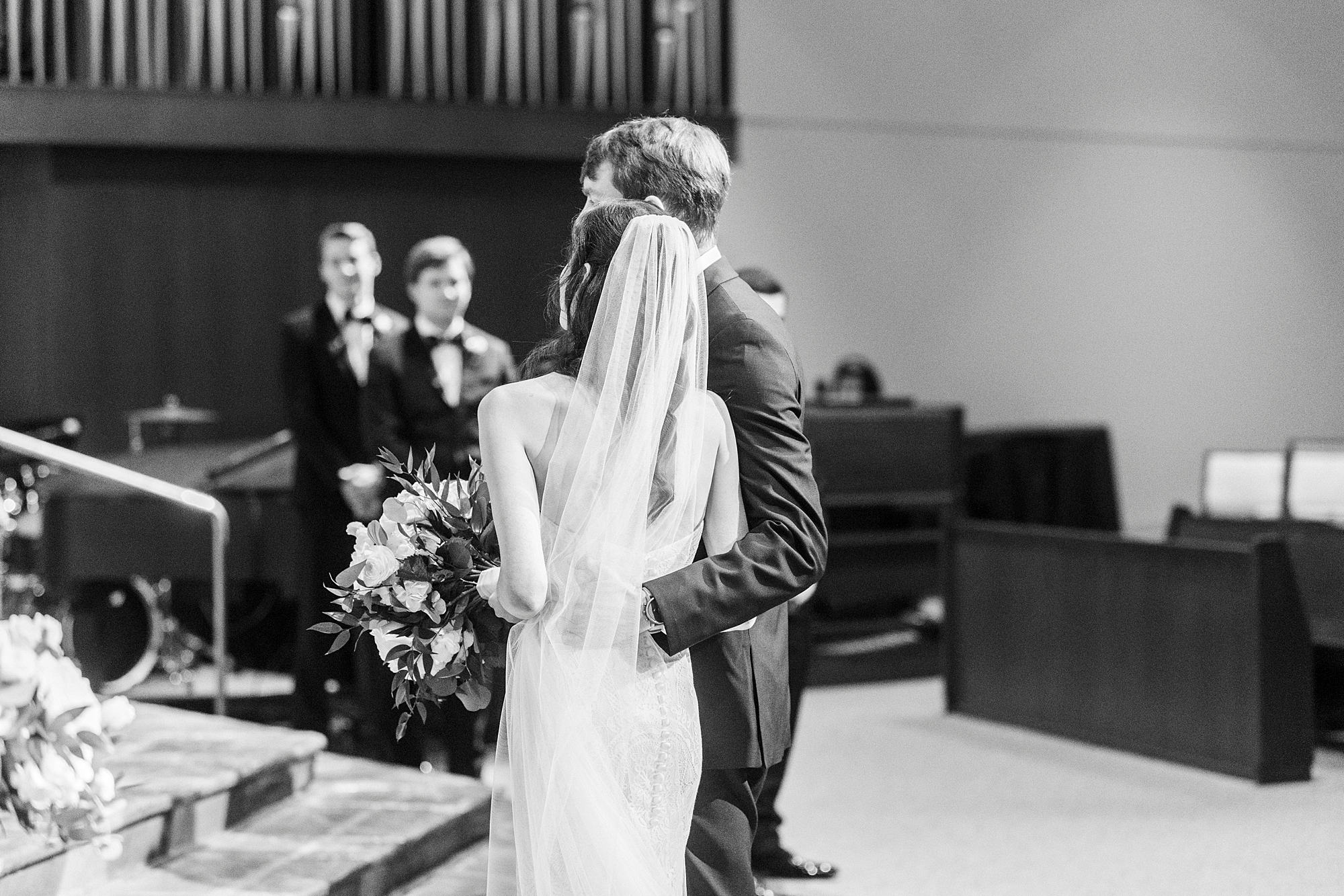 groom hugs bride at alter during wedding ceremony at St. Gabriel Catholic Church