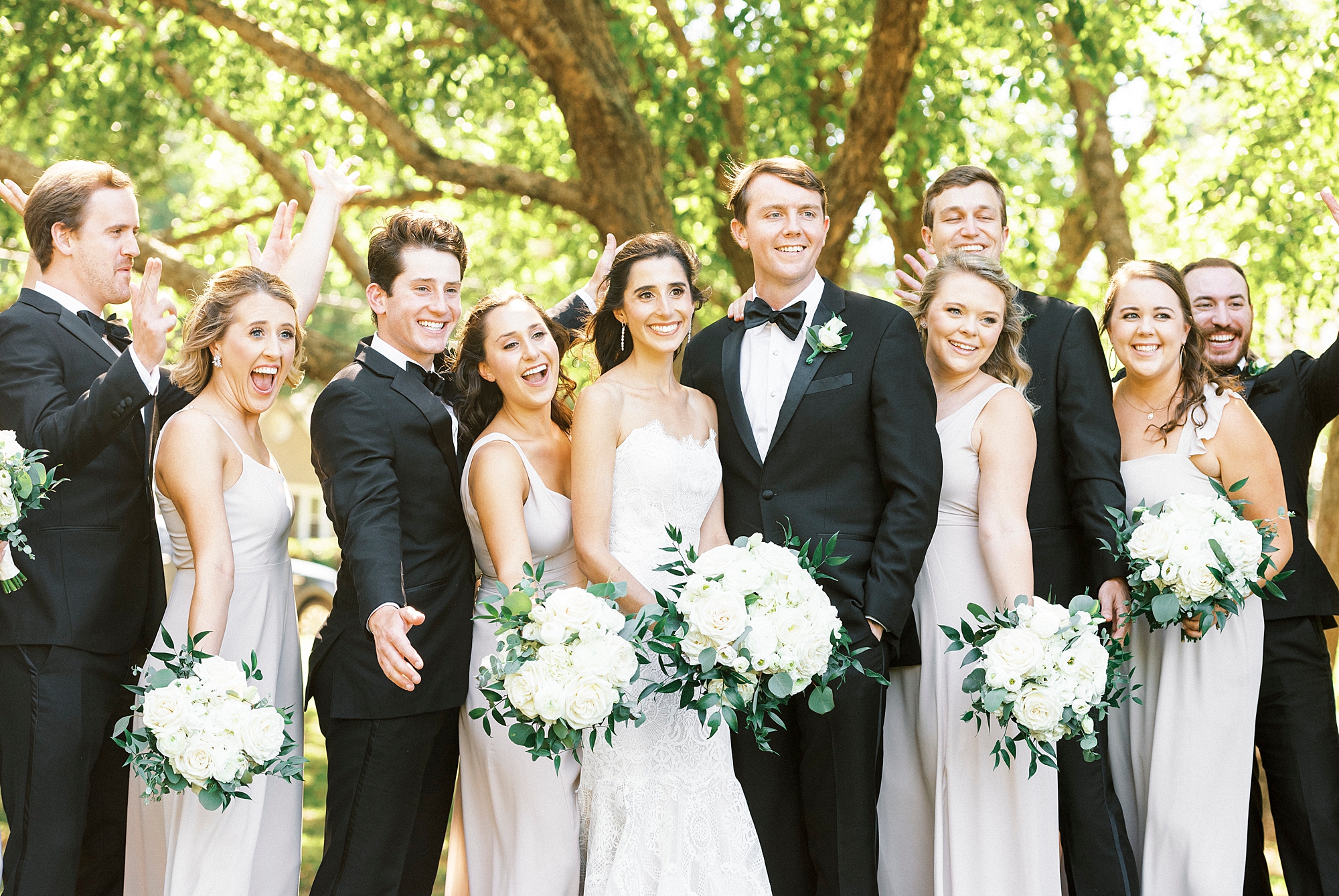 bride and groom stand with wedding party cheering around them