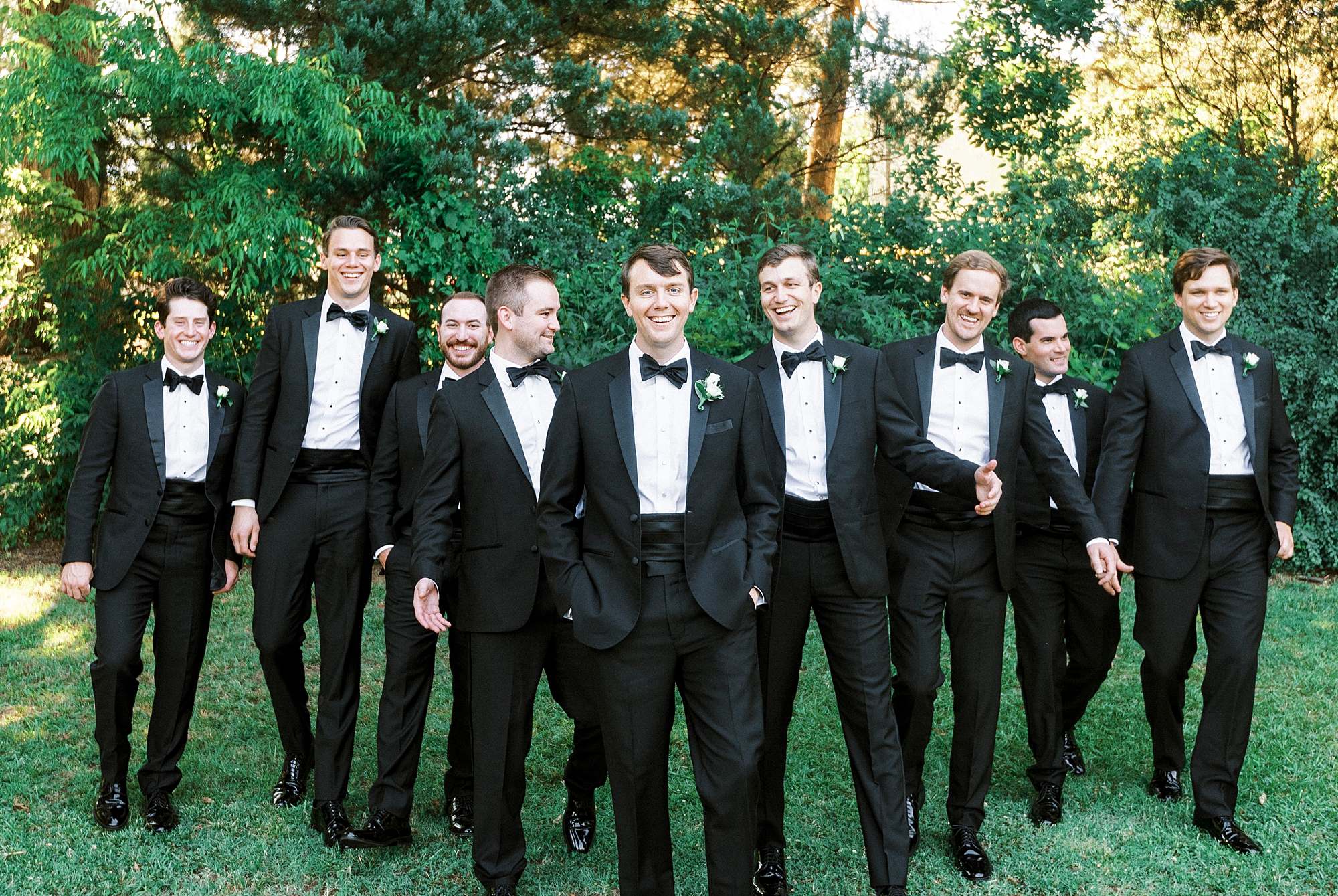 groom walks with groomsmen in classic black suits at Freedom Park