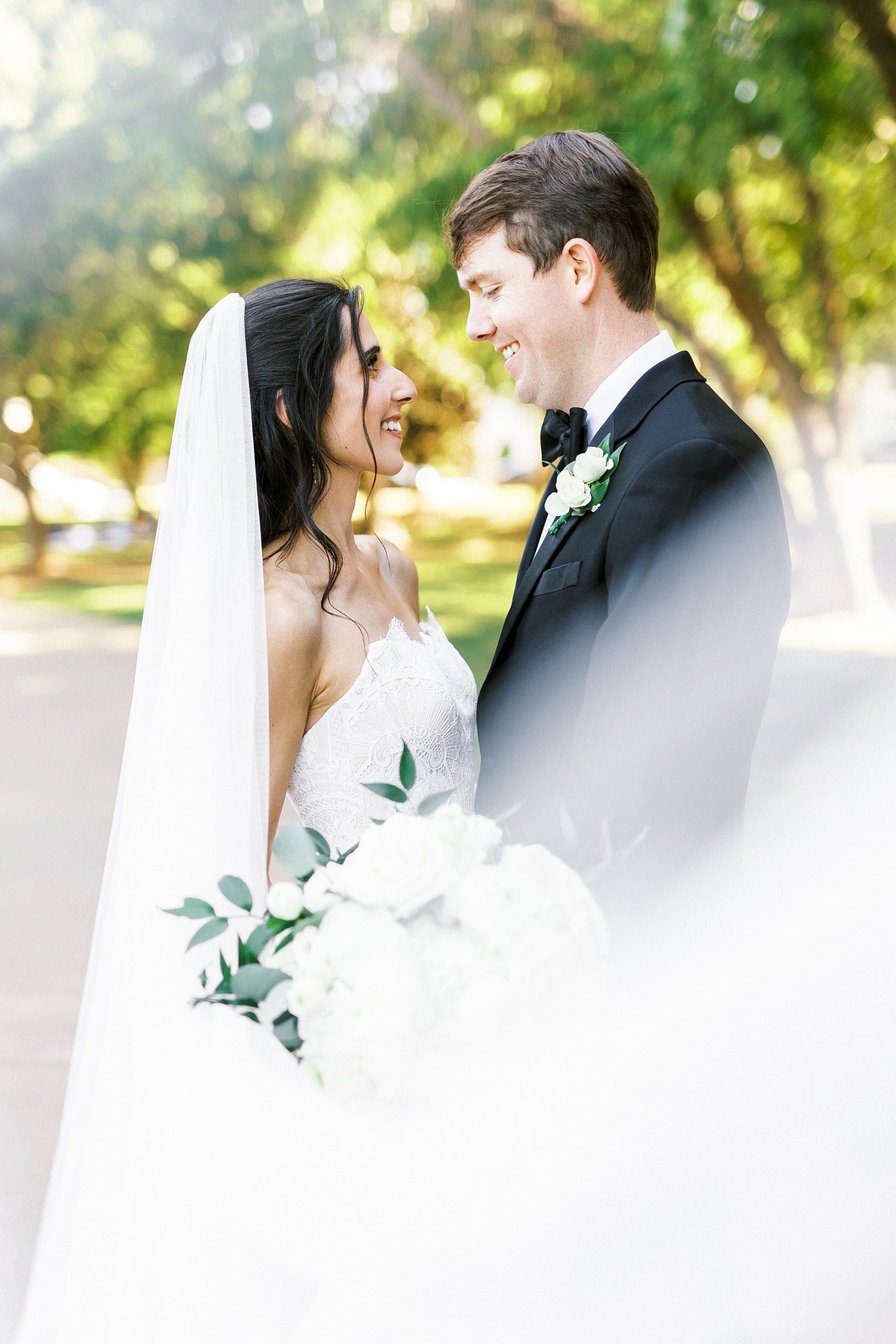 newlywed smile together with bride's veil around them in Freedom Park
