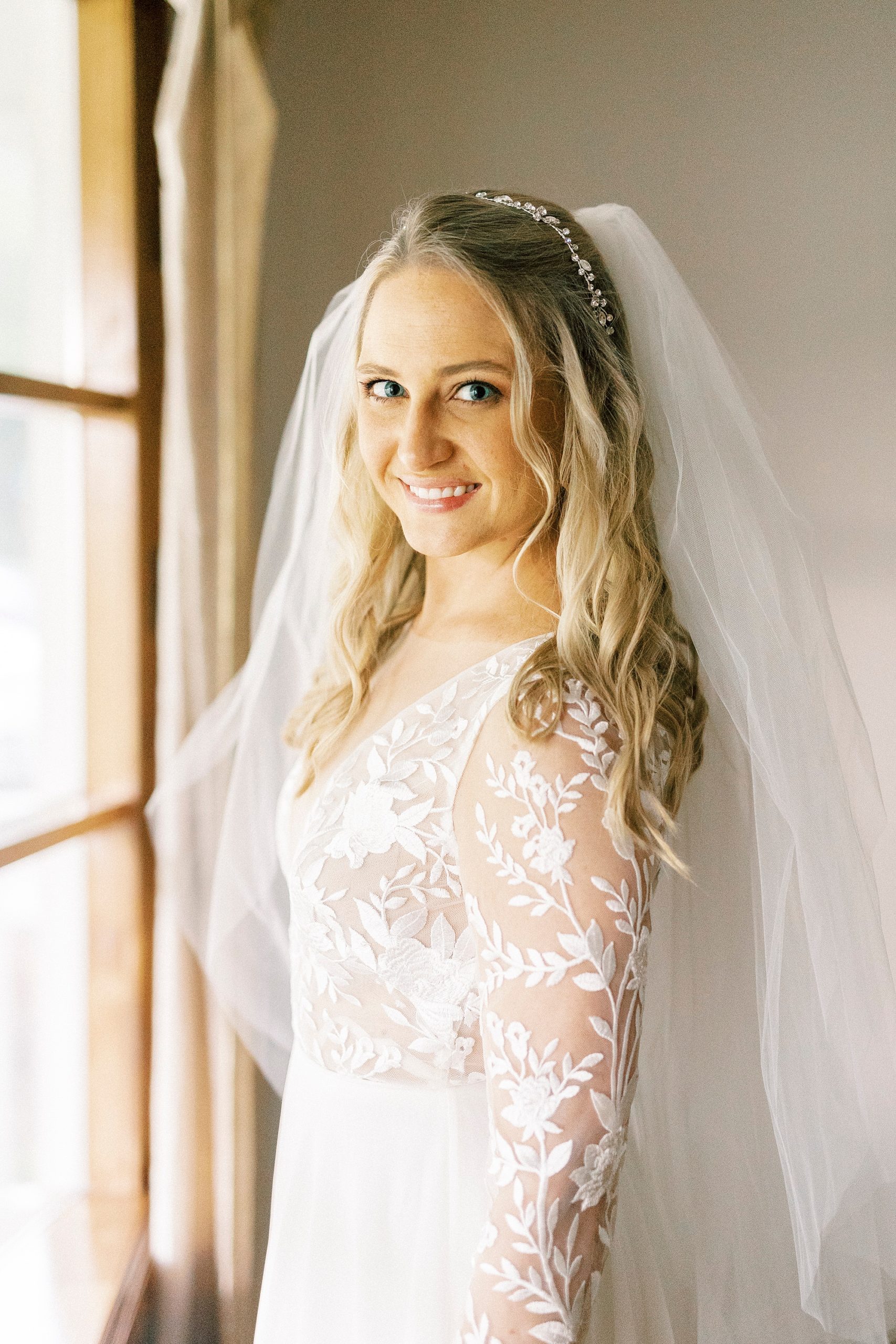 bride smiles by wooden window during bridal portraits in Lenoir NC