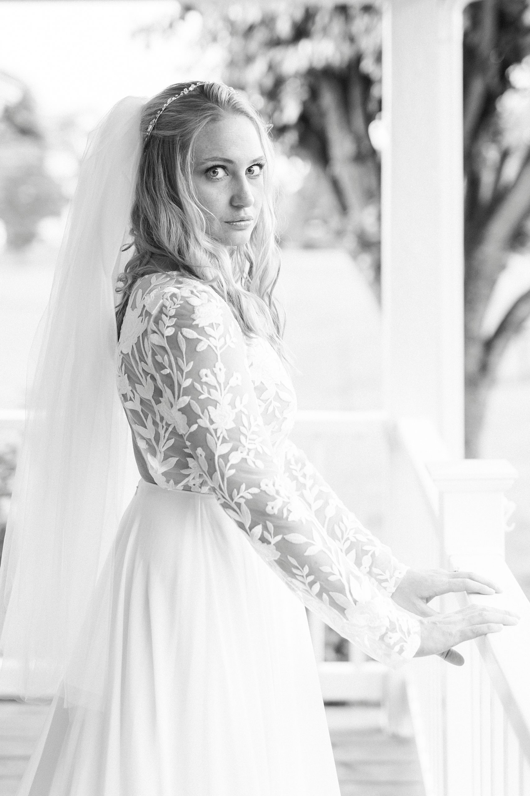 bride looks over shoulder in wedding gown on porch 