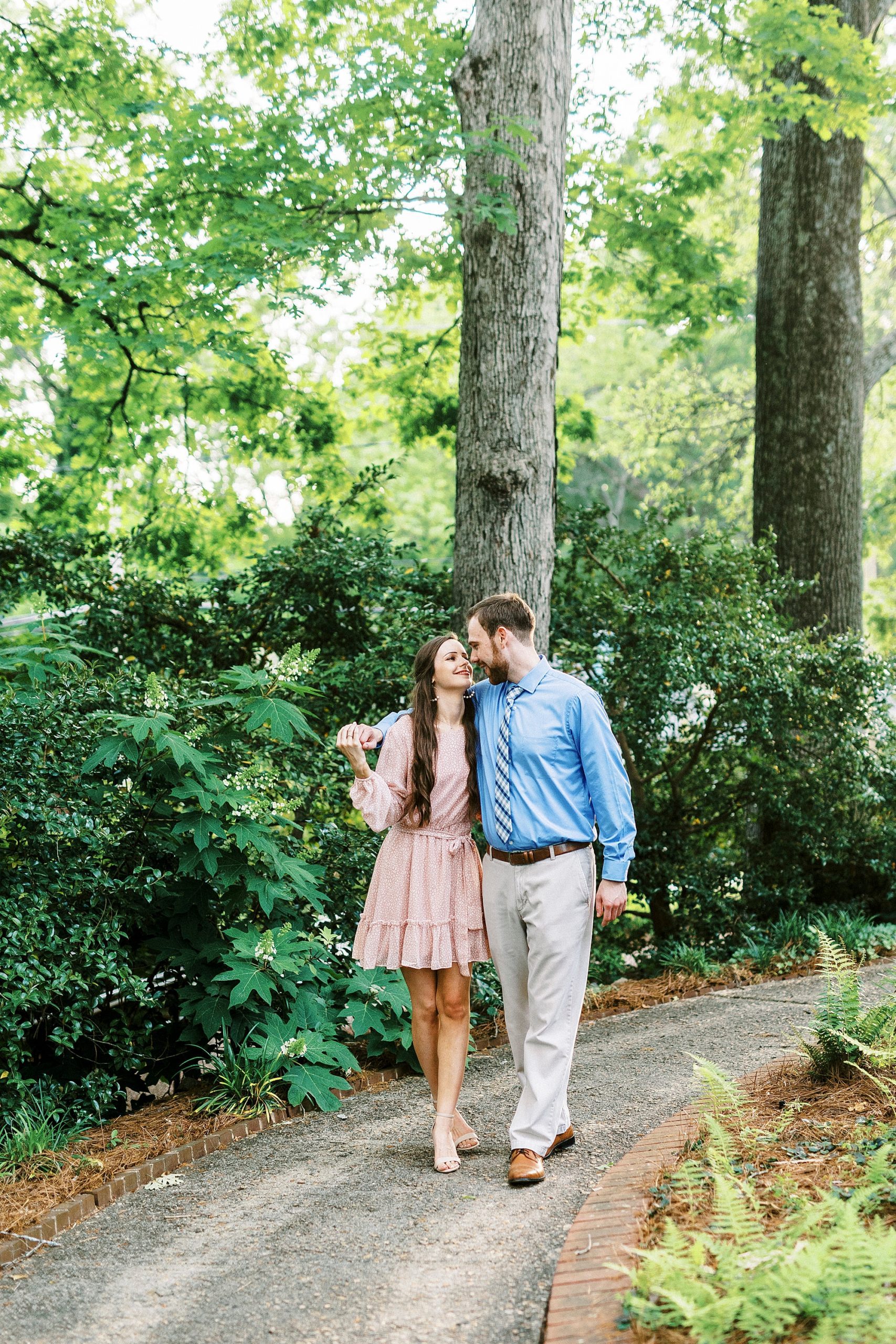 engaged couple walks through path in Glencairn Gardens