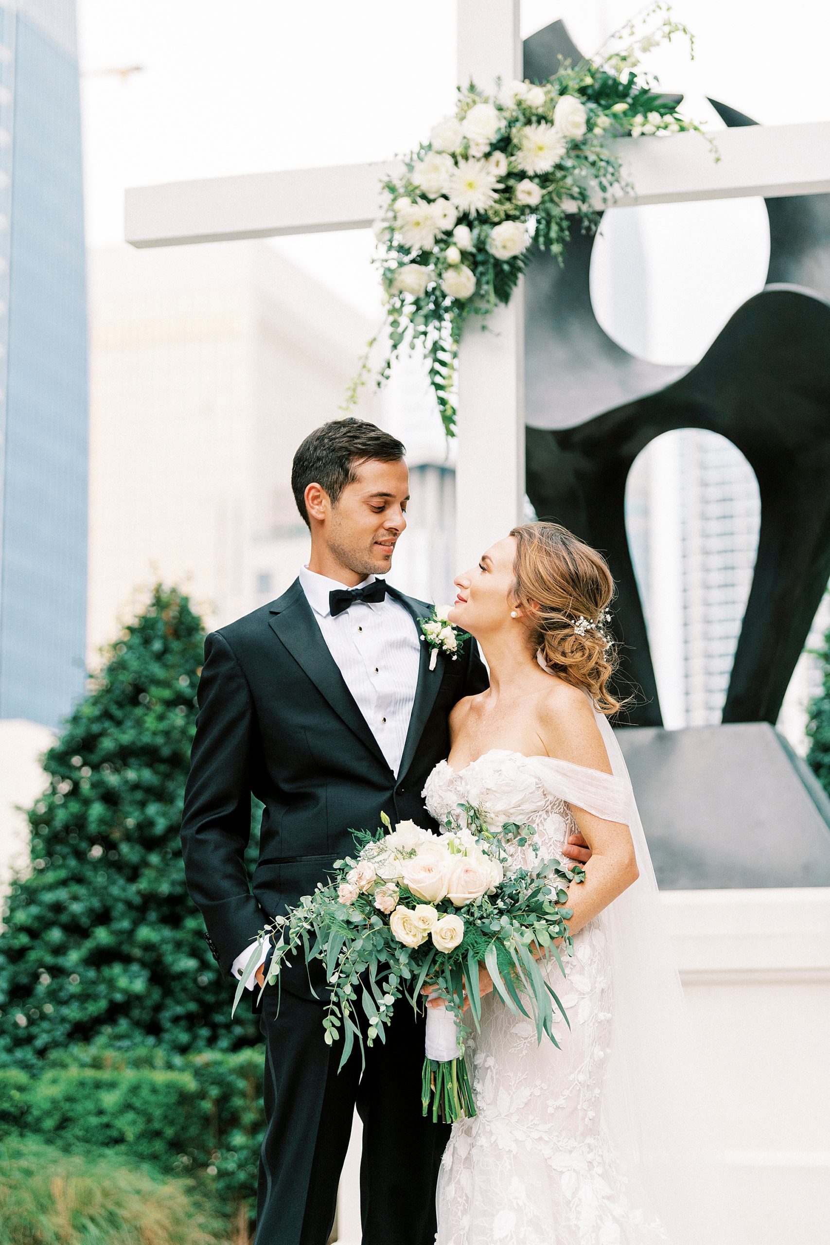 bride and groom look at each other by sculpture in garden at The Grand Bohemian Hotel