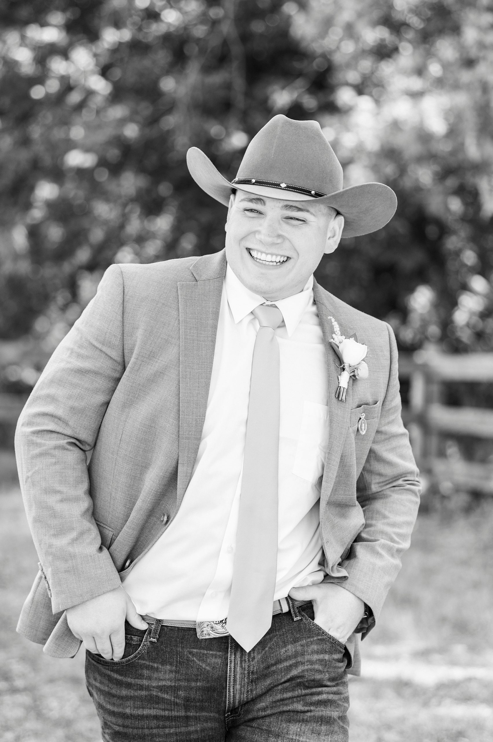 groom smiles wearing cowboy hat and jeans