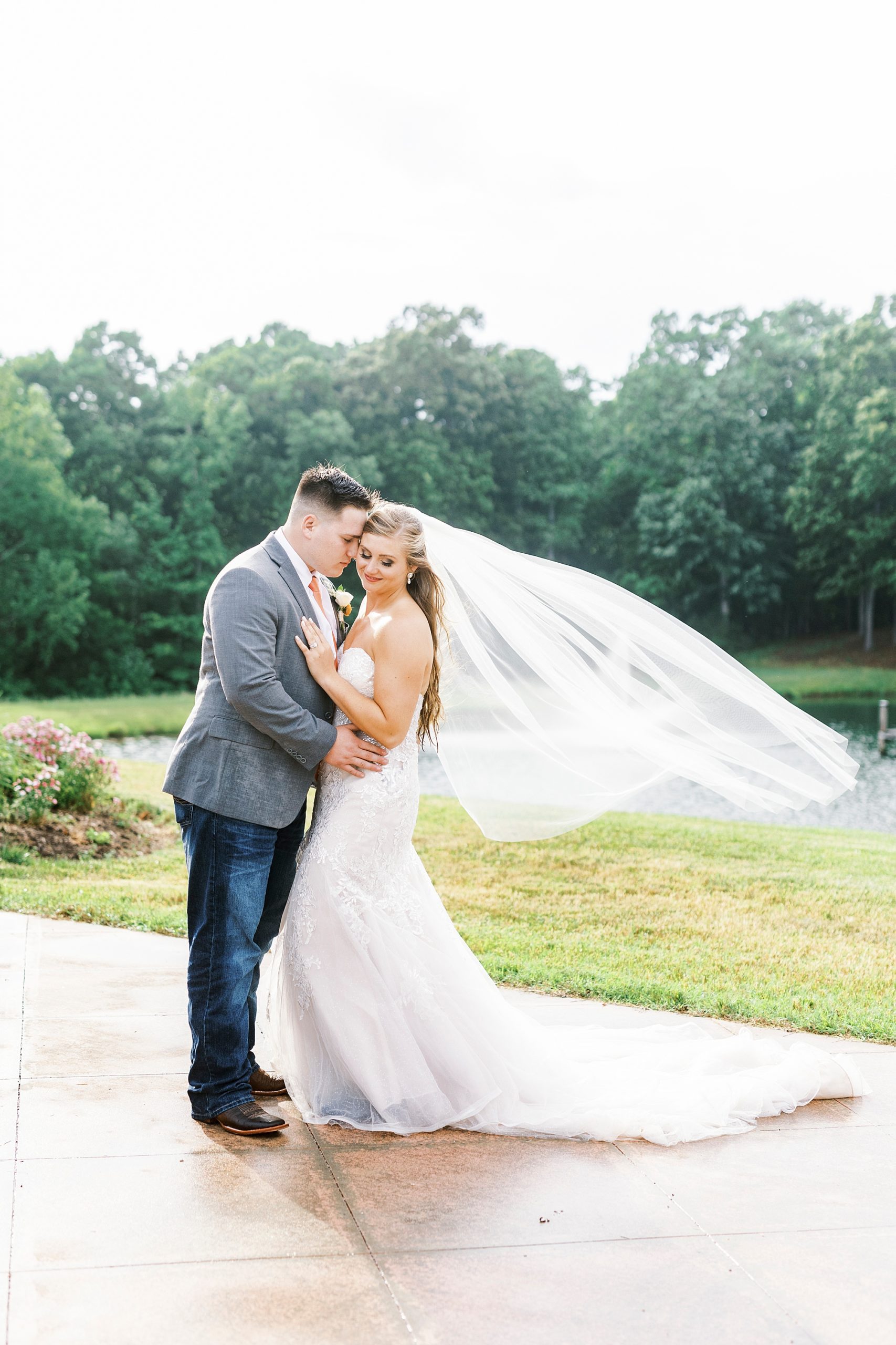 groom nuzzles bride's cheek with veil floating behind her