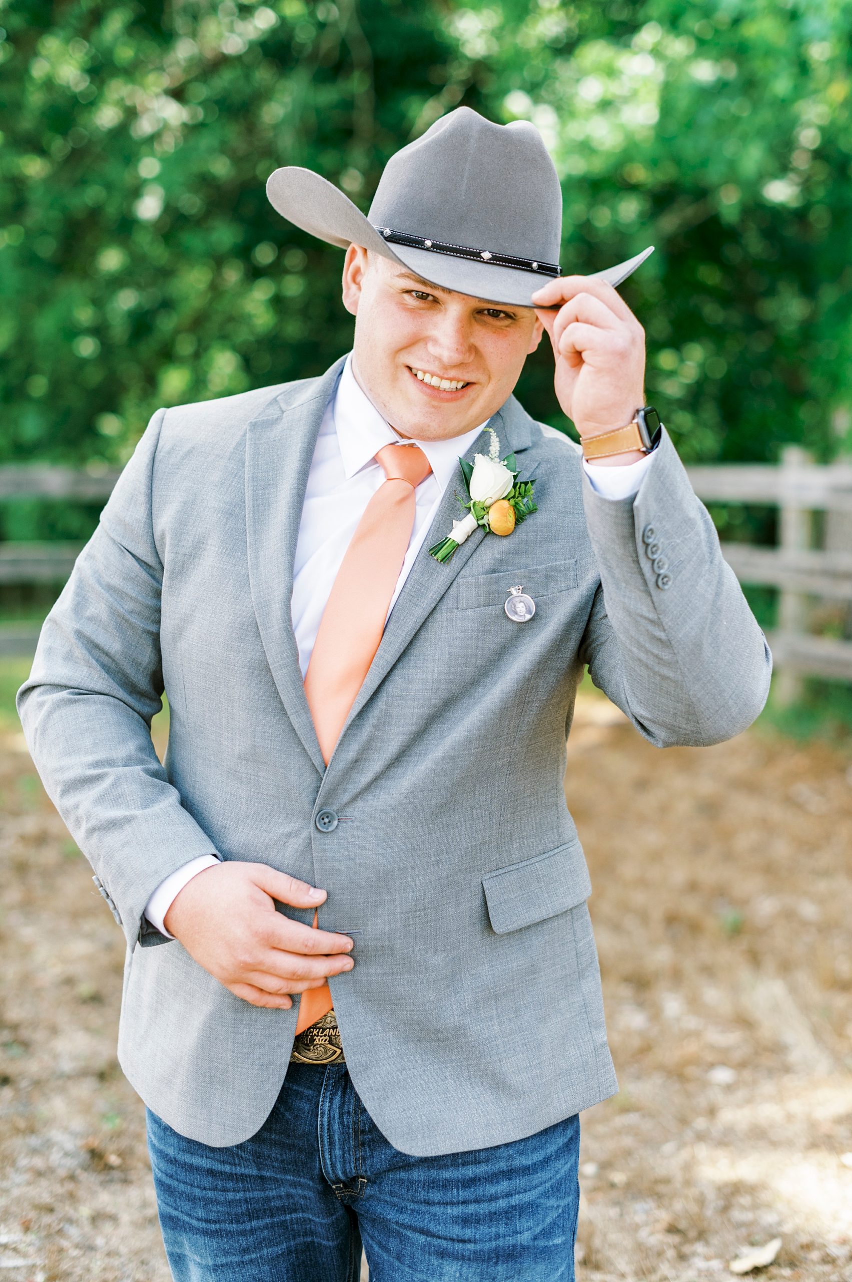 groom dips cowboy hat down during wedding photos at The Stable at Riverview