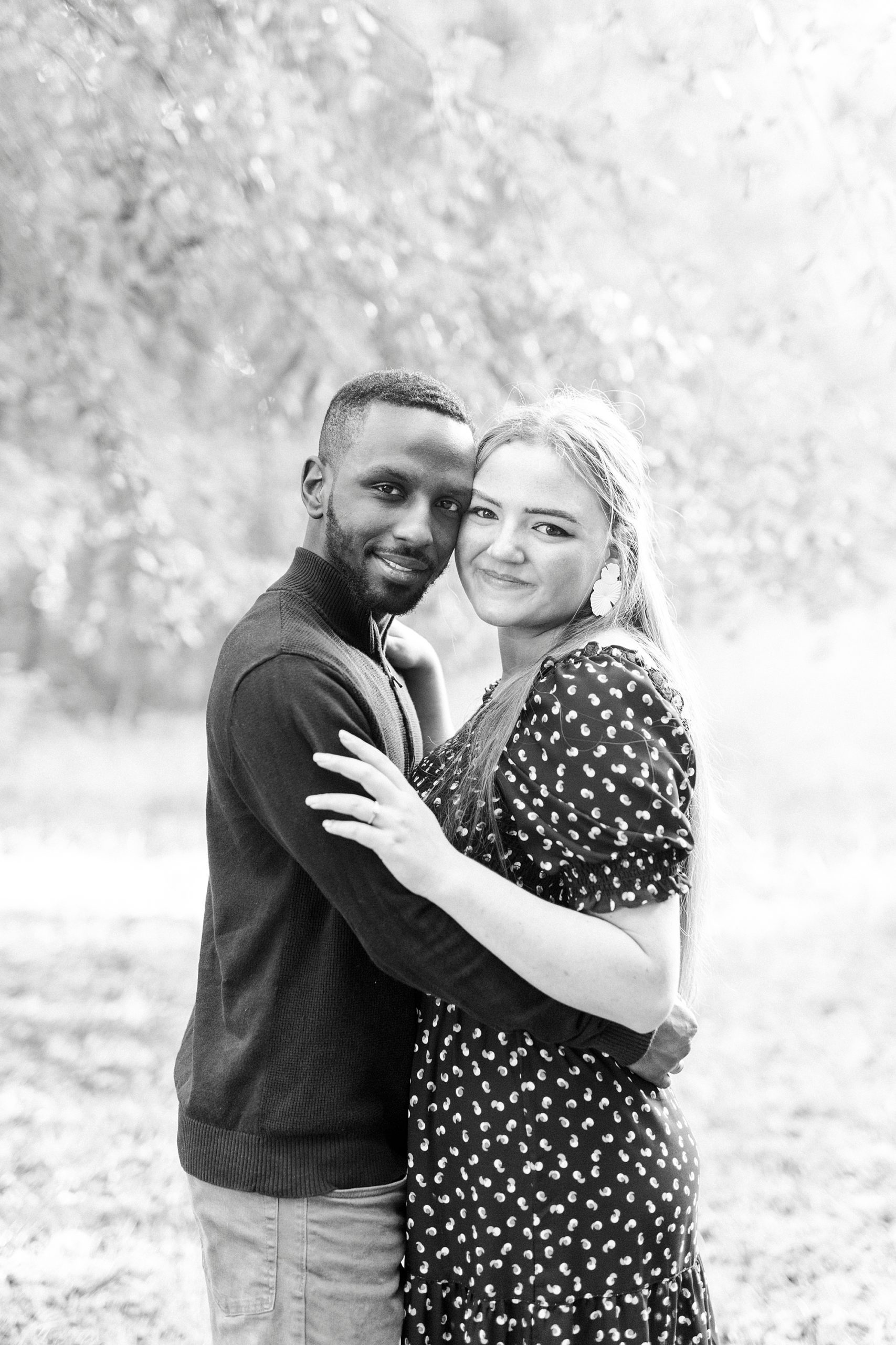 engaged couple stands together leaning heads in
