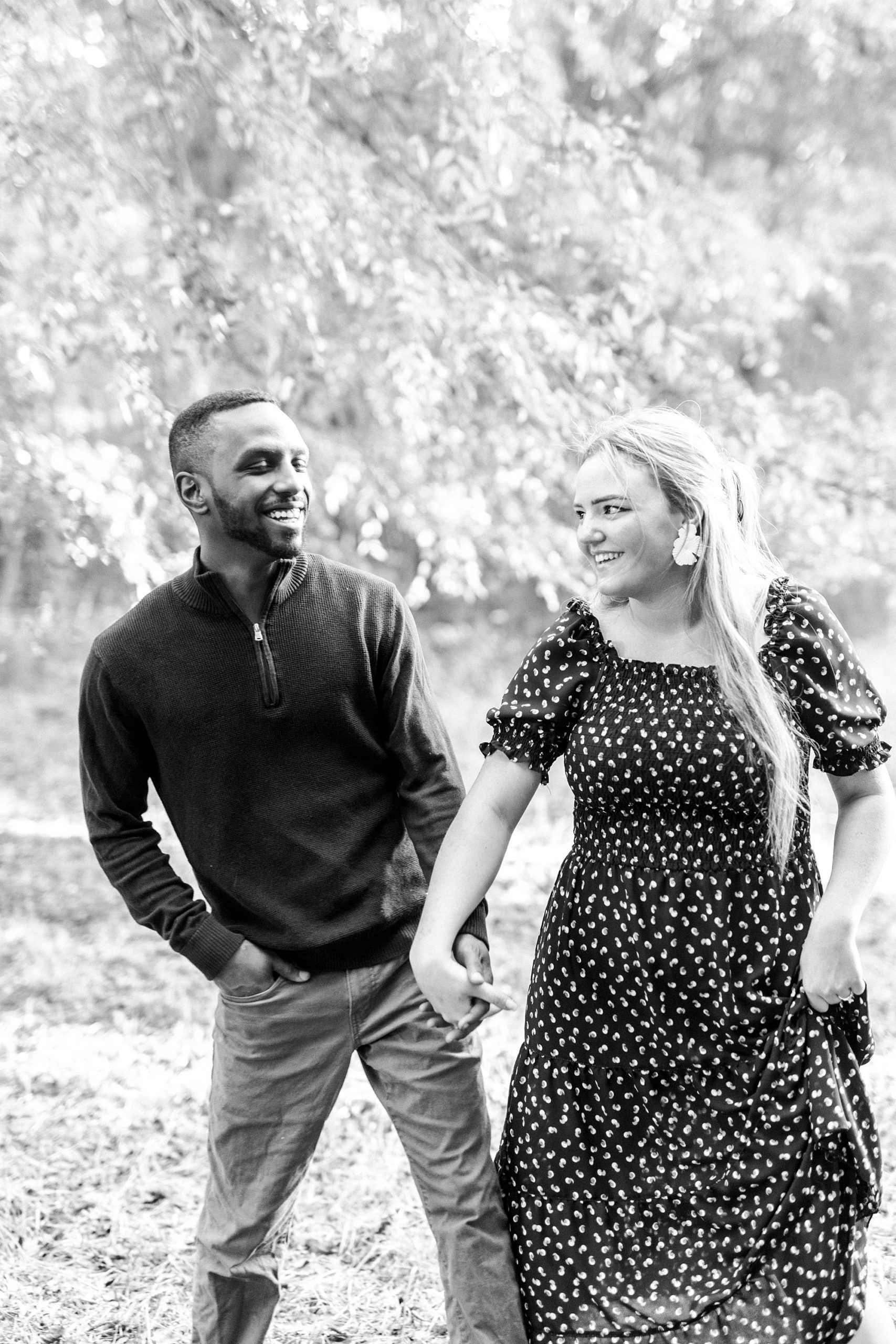 couple holds hands walking through lawn at Bella Terra