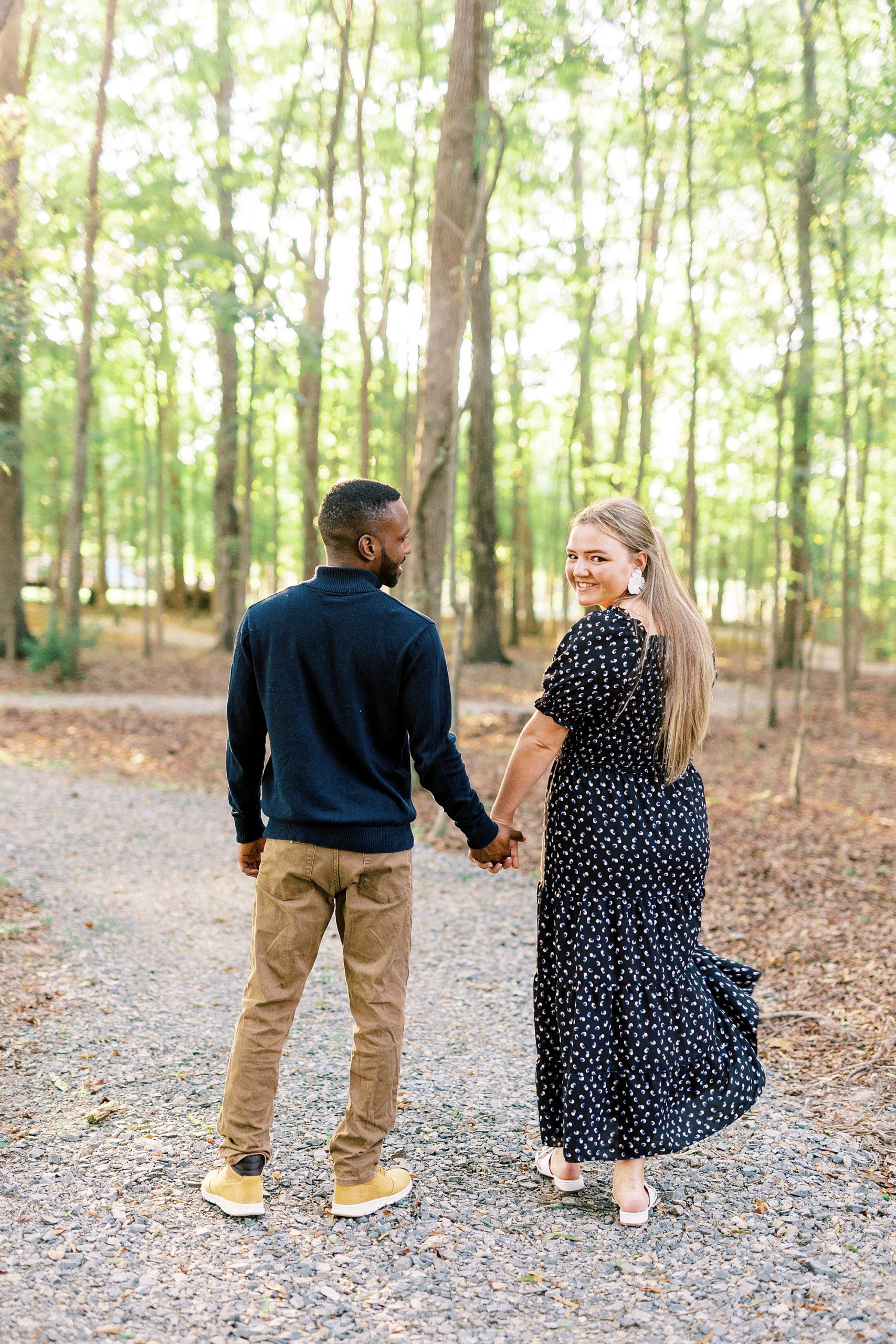 couple holds hands walking down path at Bella Terra