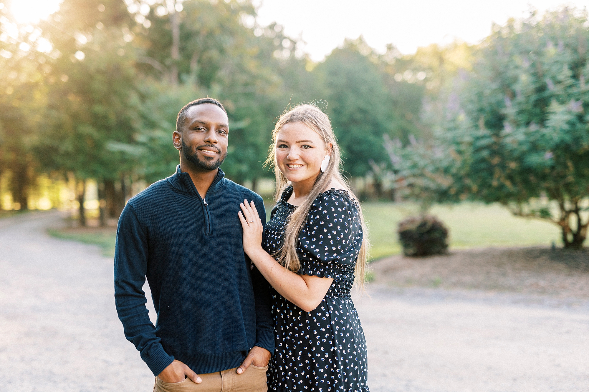 woman stands with hand on groom's chest showing off ring