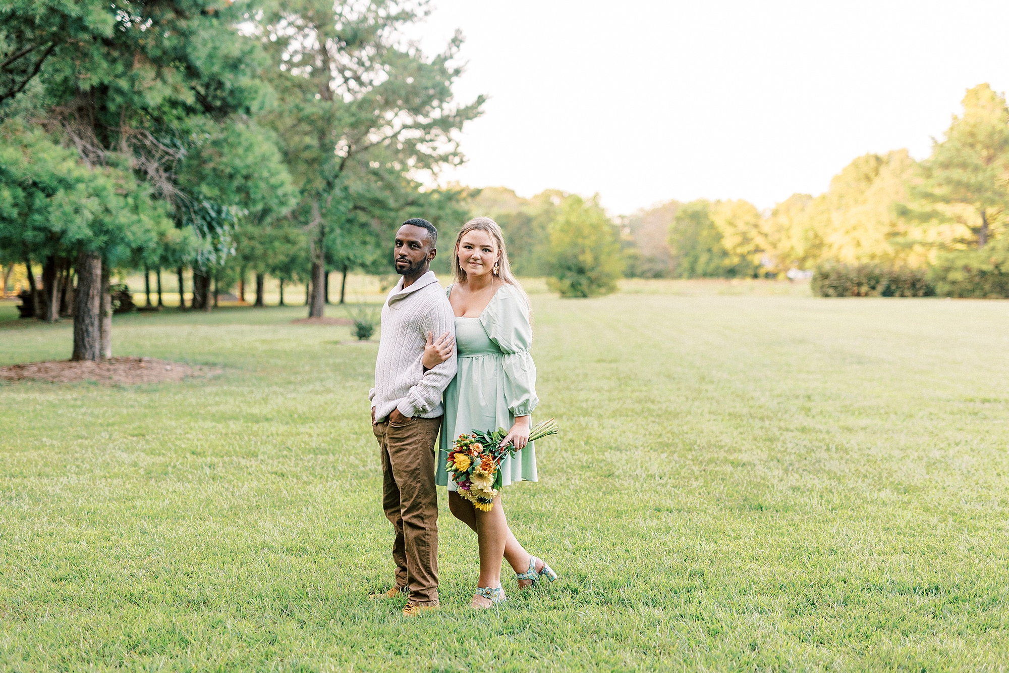 bride holds groom's arms in field at Bella Terra