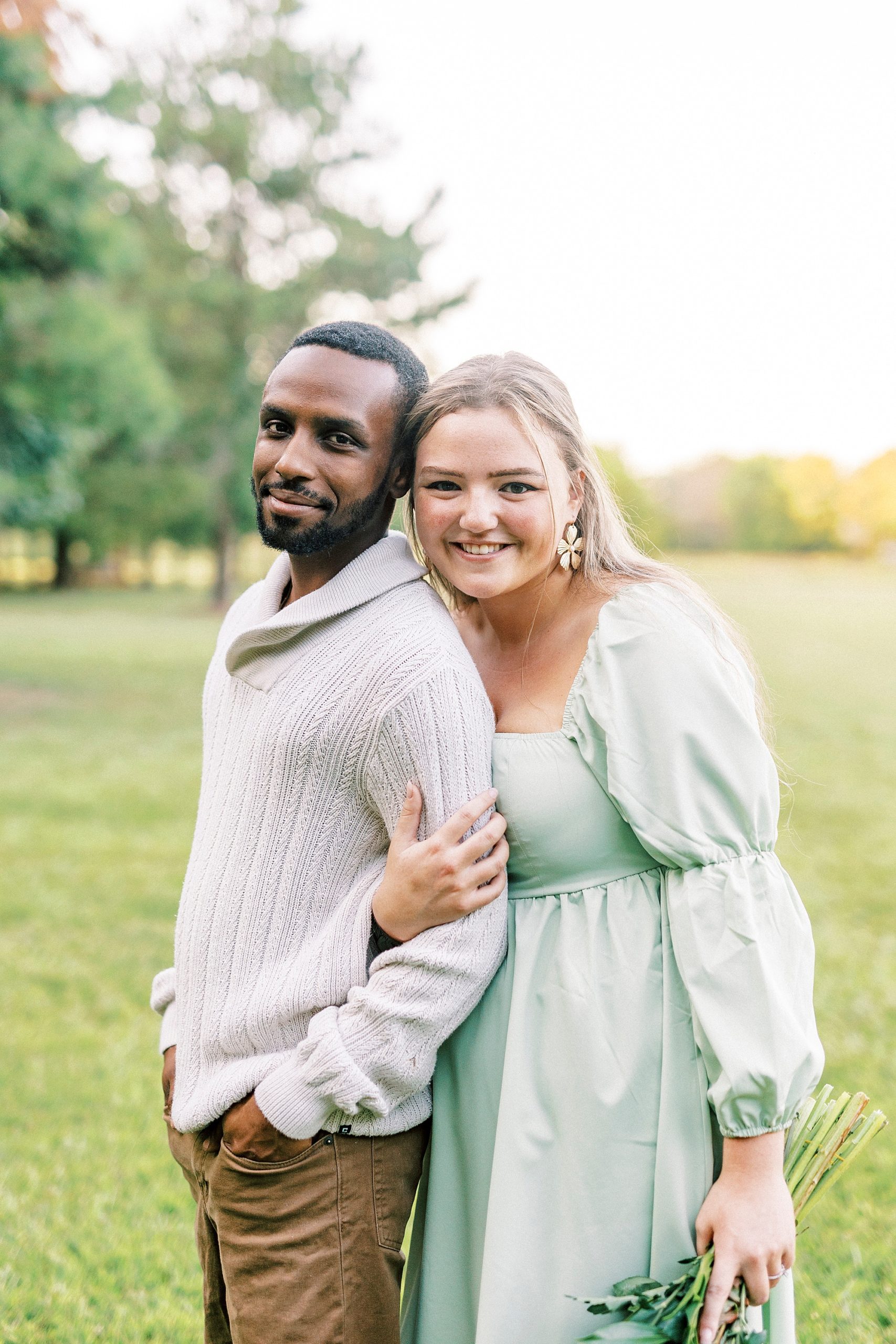 bride leans into groom's back standing on lawn