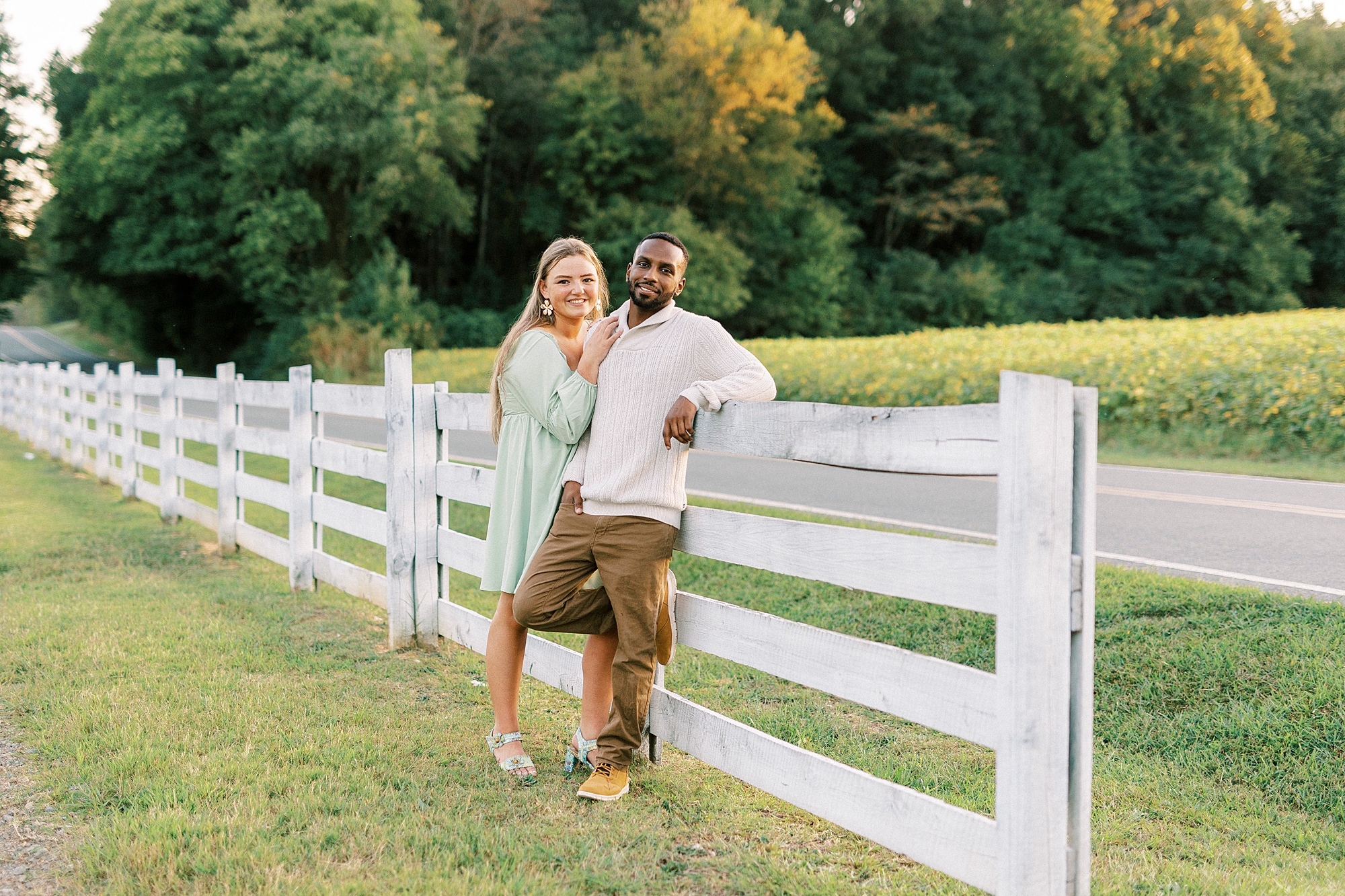 bride and groom lean against white wooden fence at Bella Terra