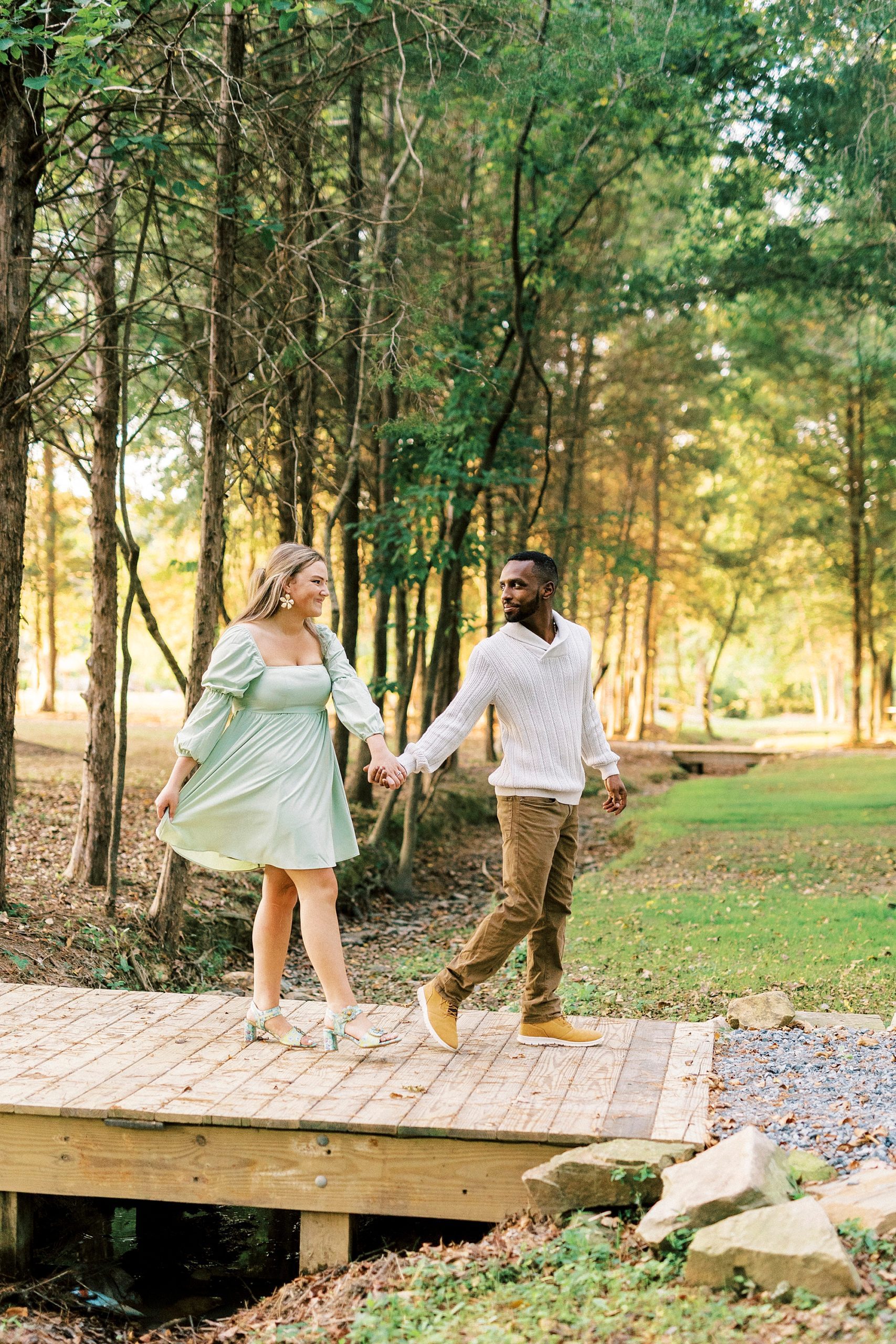 couple holds hands walking on wooden dock at Bella Terra