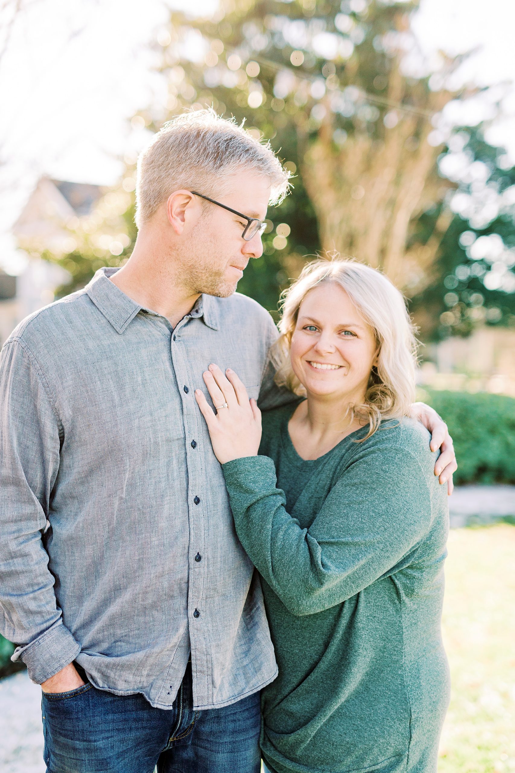 bride leans against groom's chest during Downtown Monroe engagement portraits