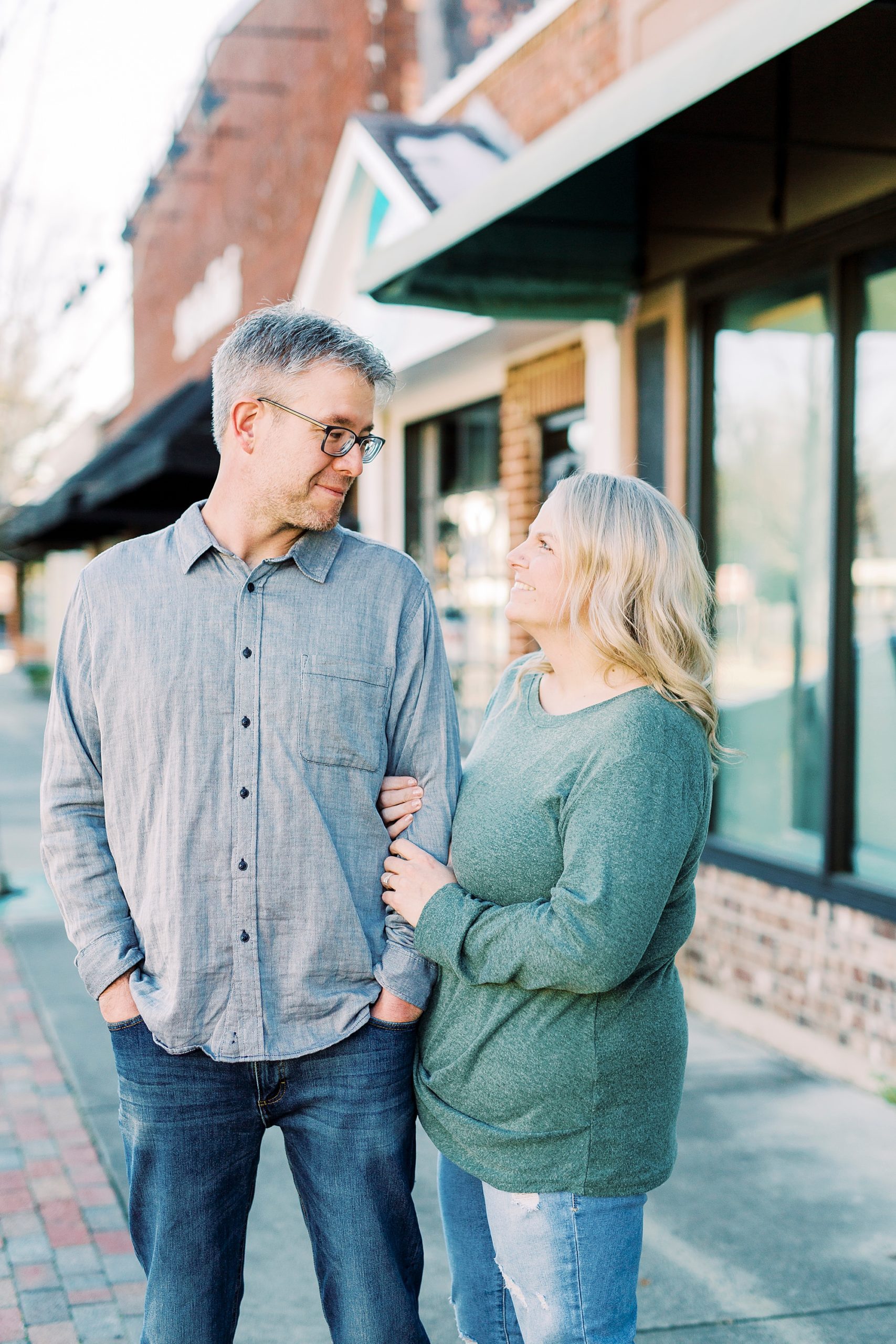 bride looks up at groom during cozy fall Downtown Monroe engagement portraits