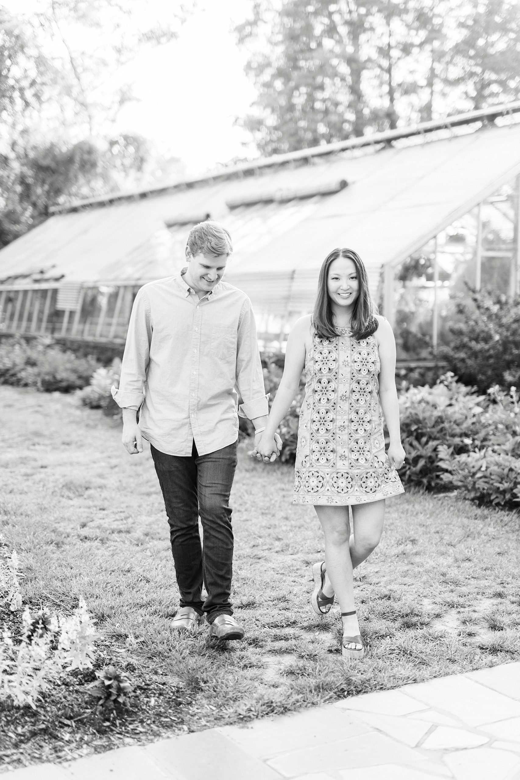 engaged couple walks on lawn during Reynolda Gardens engagement portraits