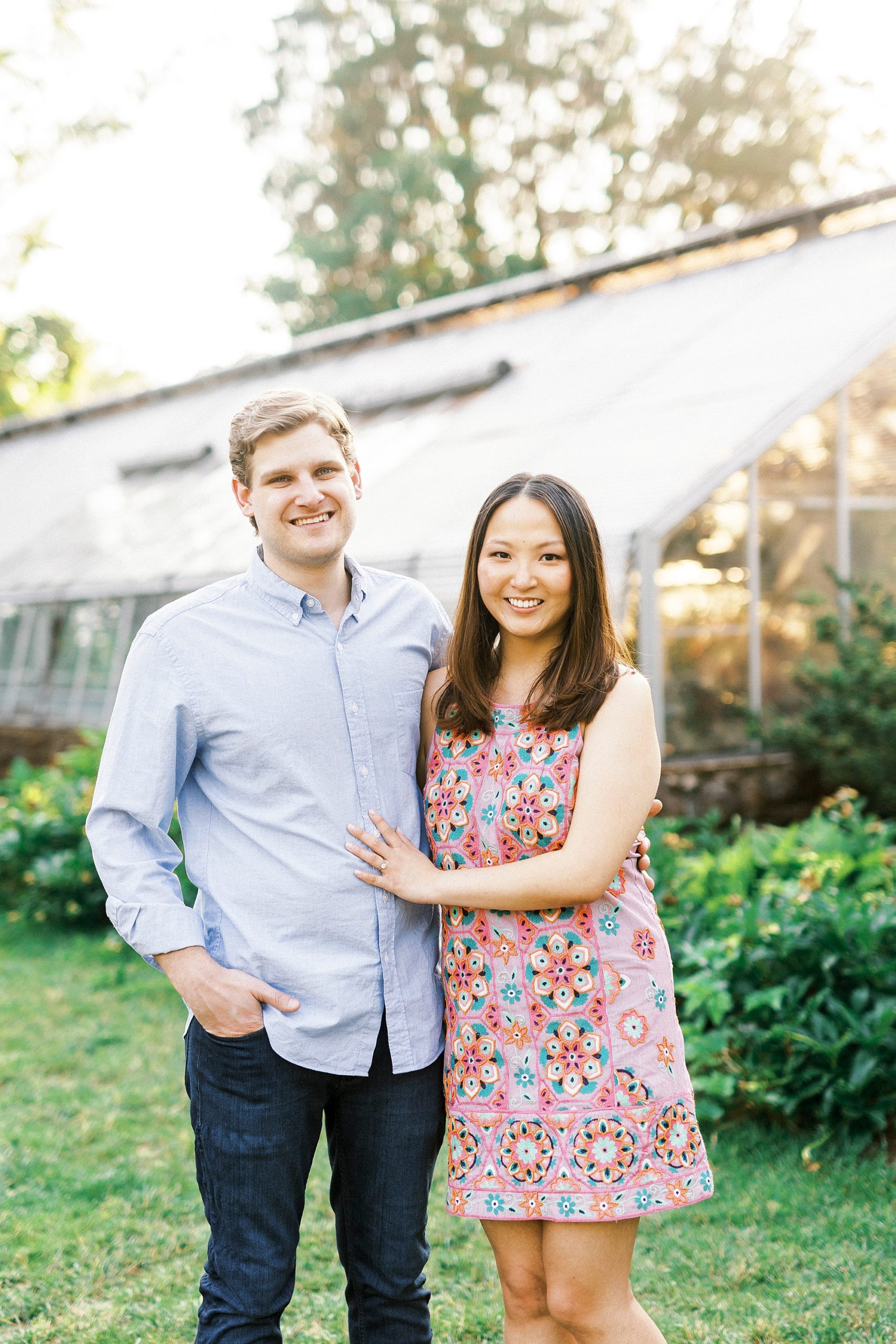 woman hugs fiancee in blue shirt during Reynolda Gardens engagement portraits
