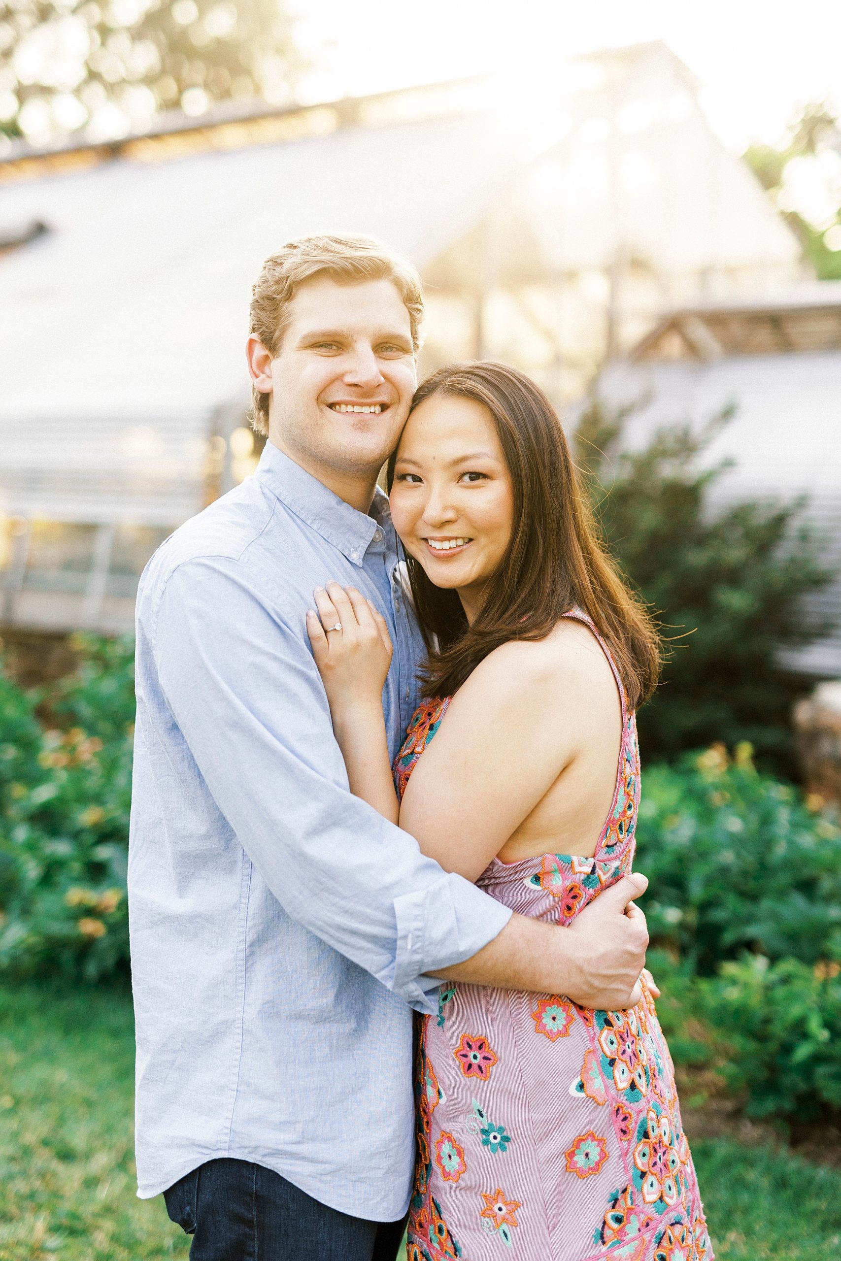 engaged couple hugs by greenhouse at Reynolda Gardens