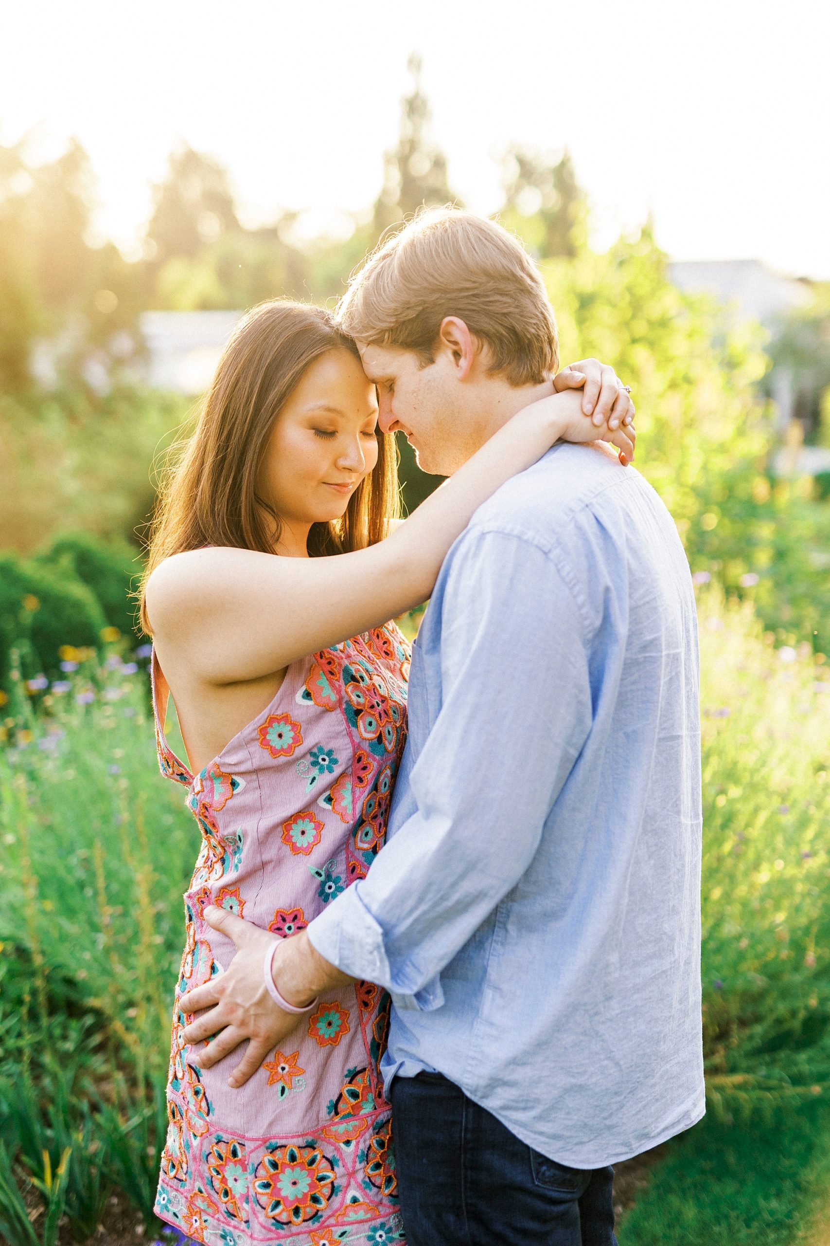 engaged couple leans foreheads together standing in Reynolda Gardens