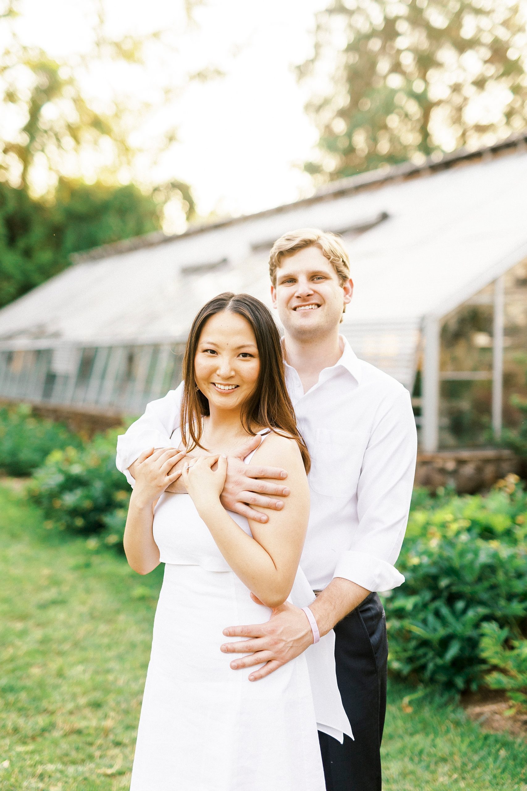 man hugs woman from behind holding her hip at Reynolda Gardens
