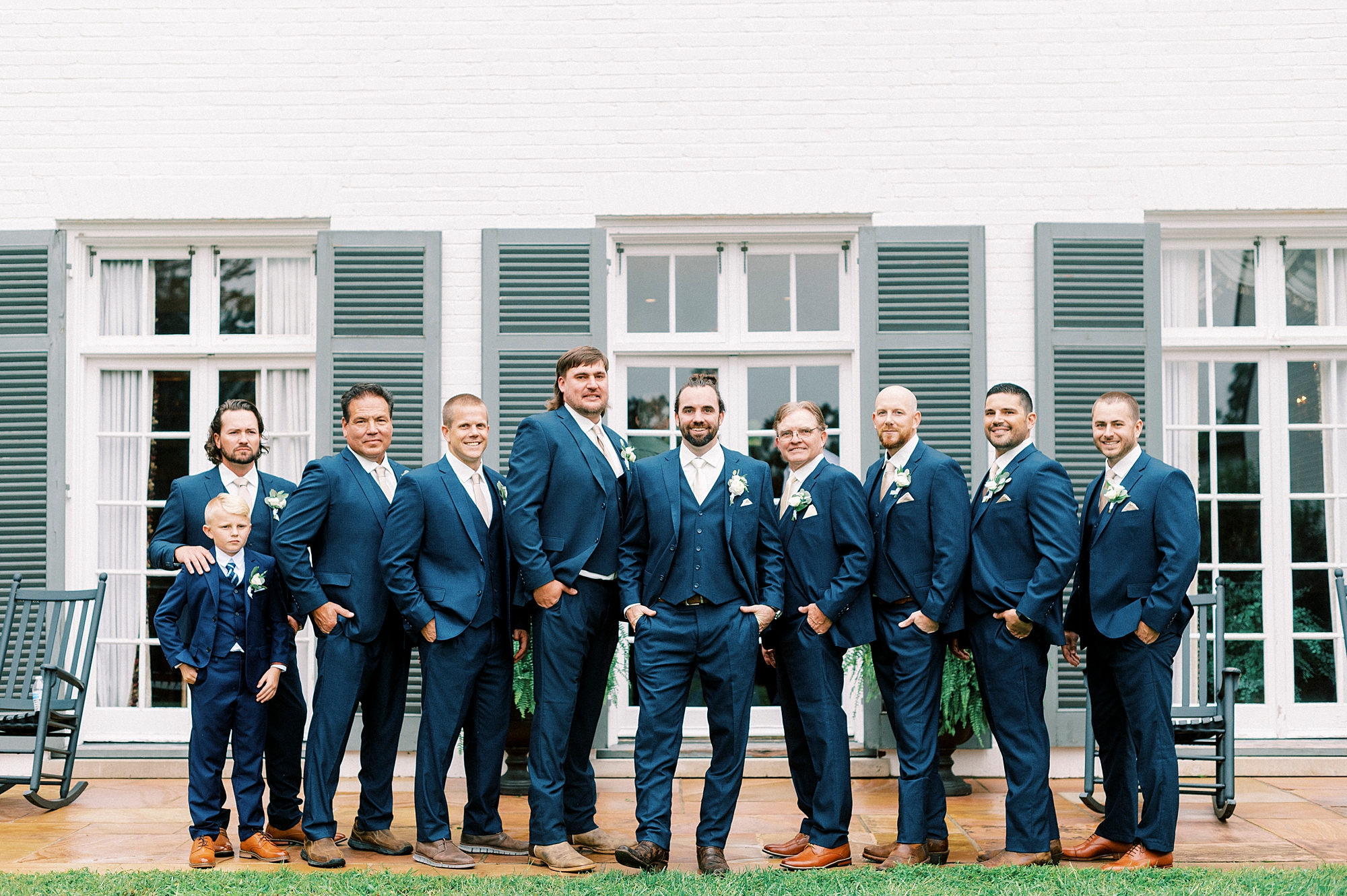 groom and groomsmen stand in navy suits outside Boxwood Estate