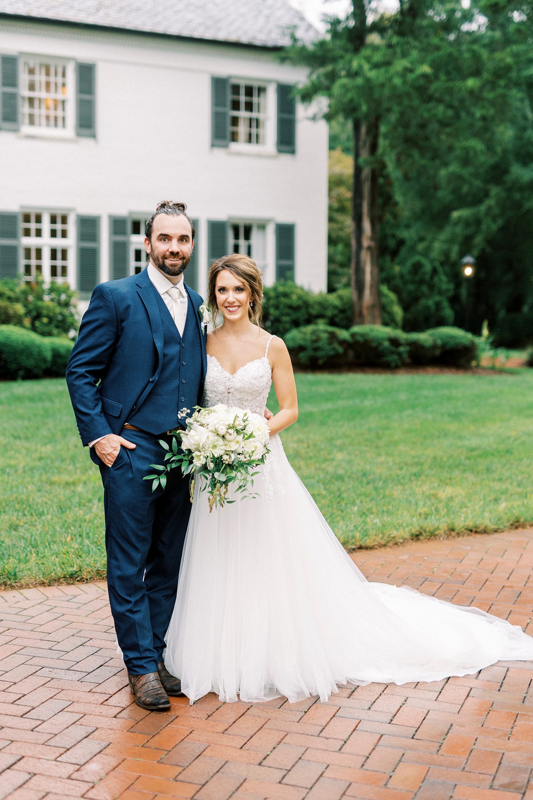 bride and groom hug on brick walkway outside Boxwood Estate