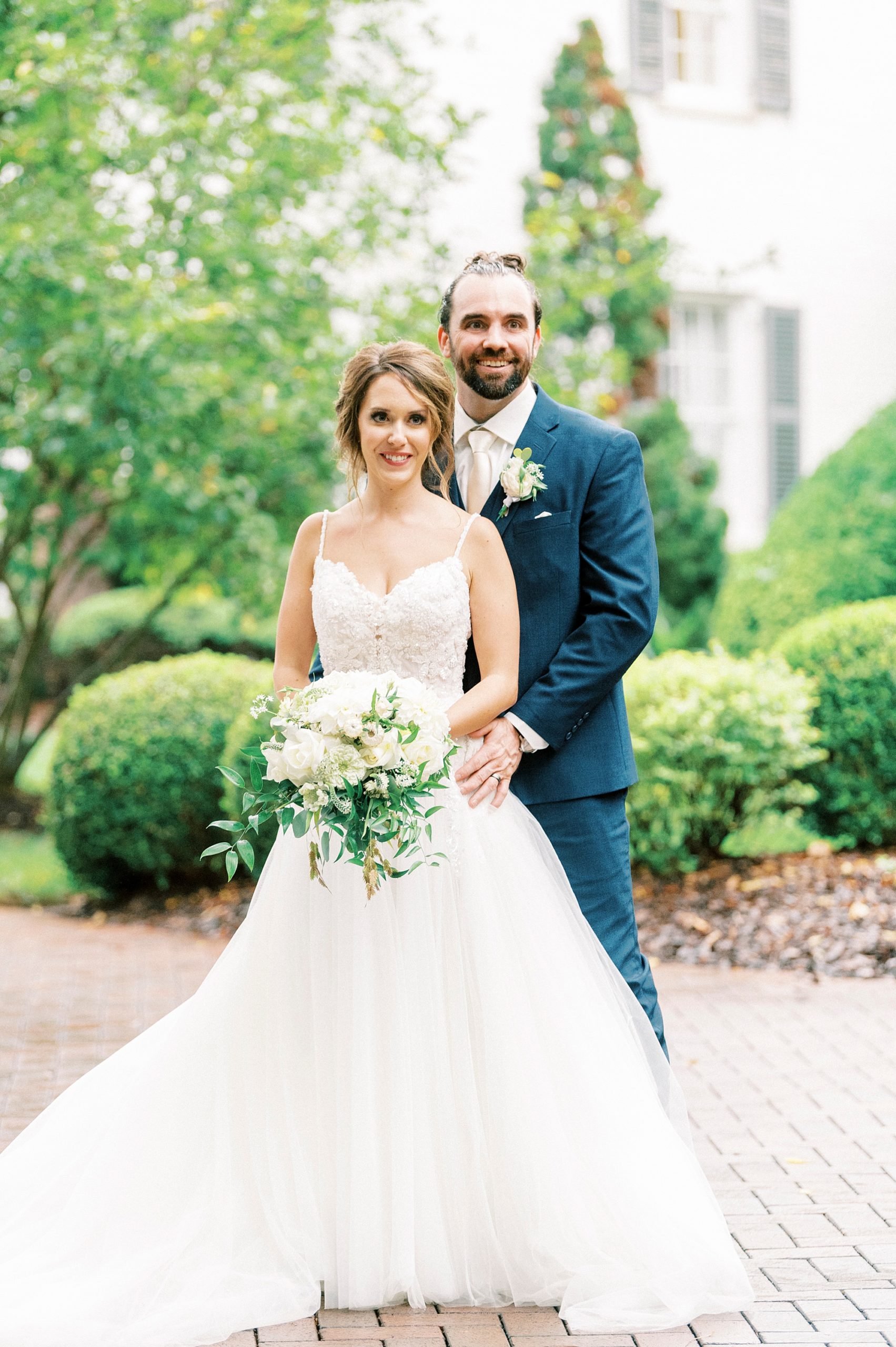 groom stands behind bride holding her hips at Boxwood Estate