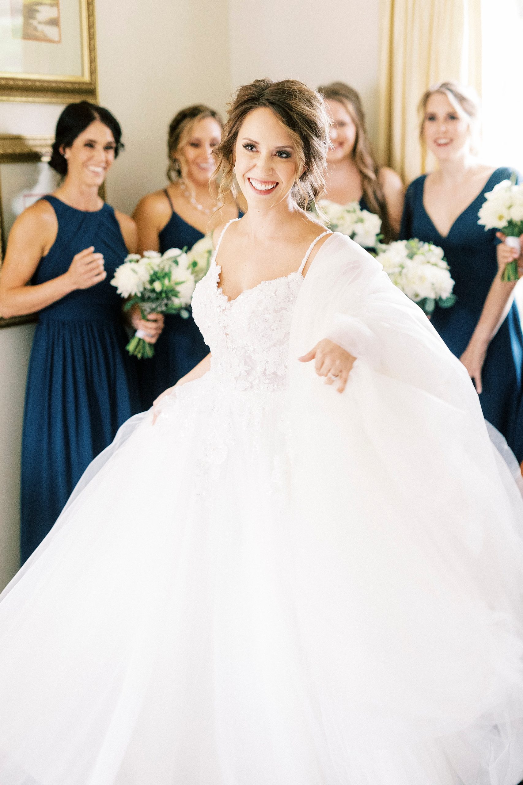 bride shows off gown showing dress to bridesmaids