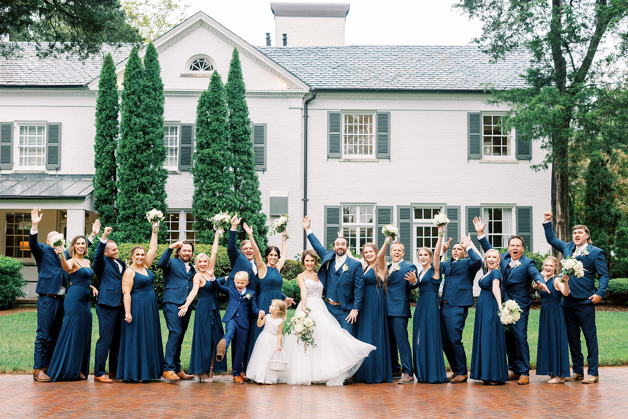 wedding party cheers during portraits outside Boxwood Estate