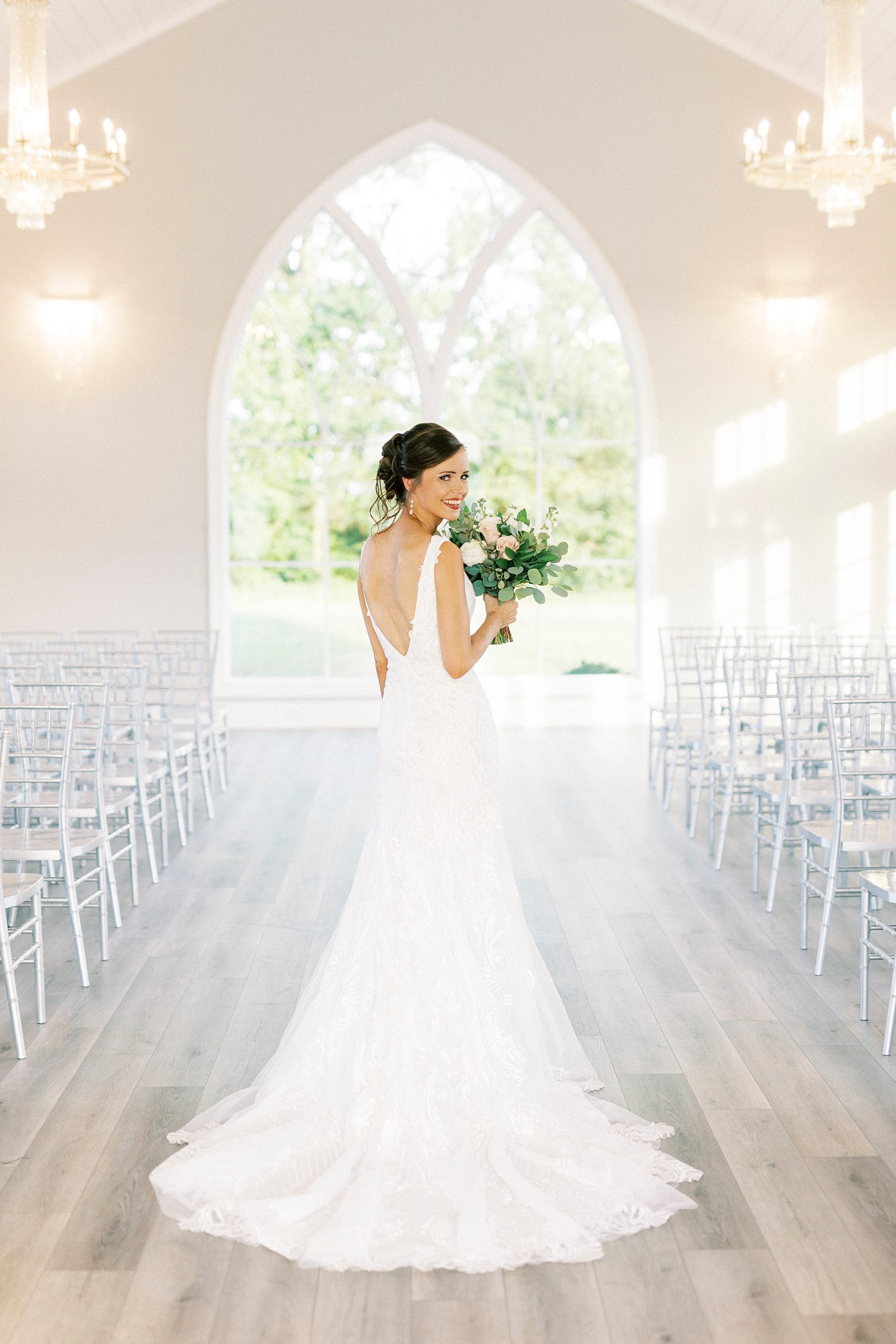 bride stands facing windows showing off back of gown at Chickadee Hill Farms