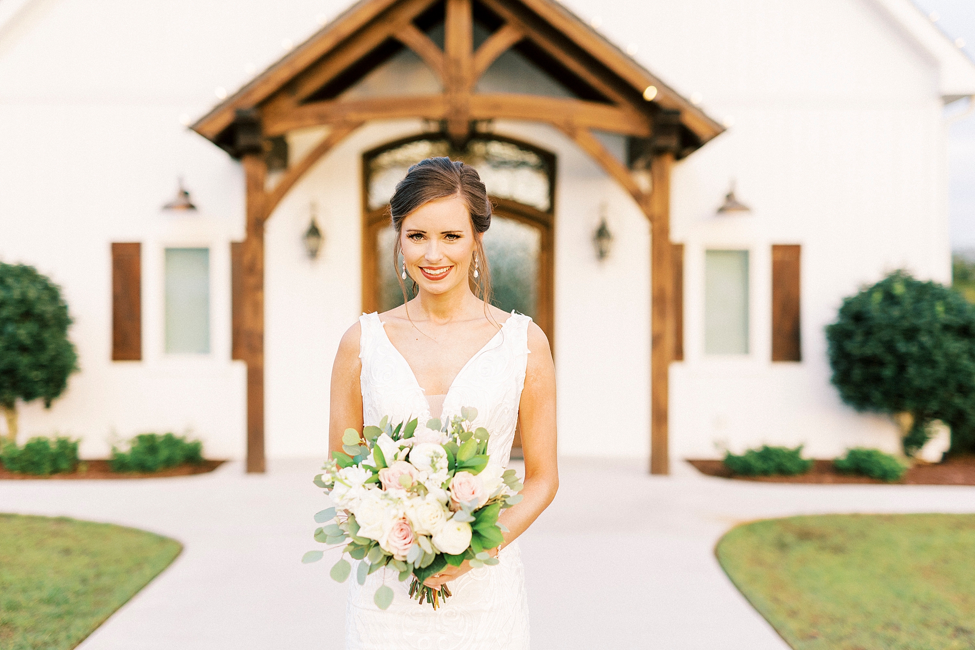 bride smiles standing outside wooden door at Chickadee Hill Farms