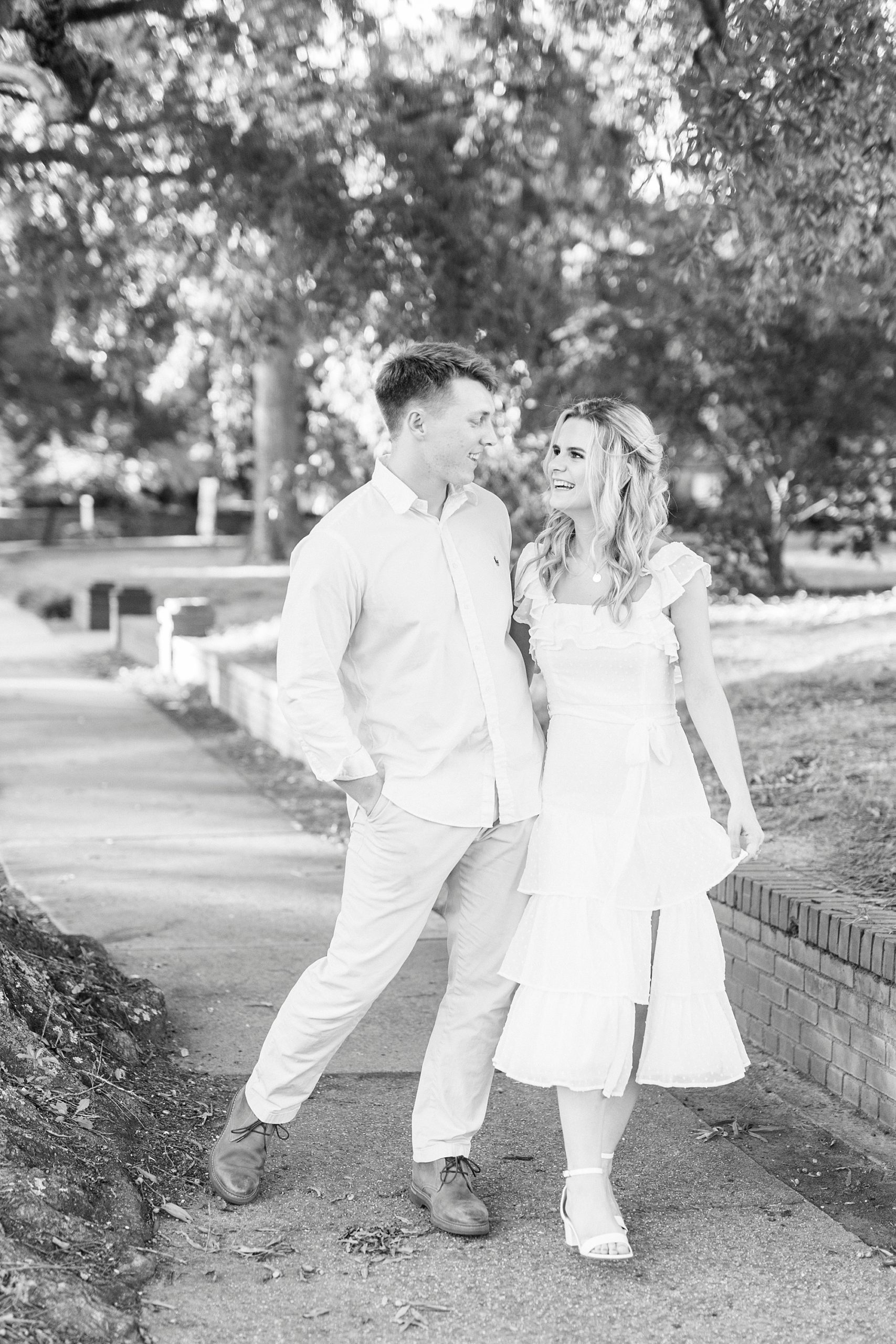 engaged couple laughs together on sidewalk