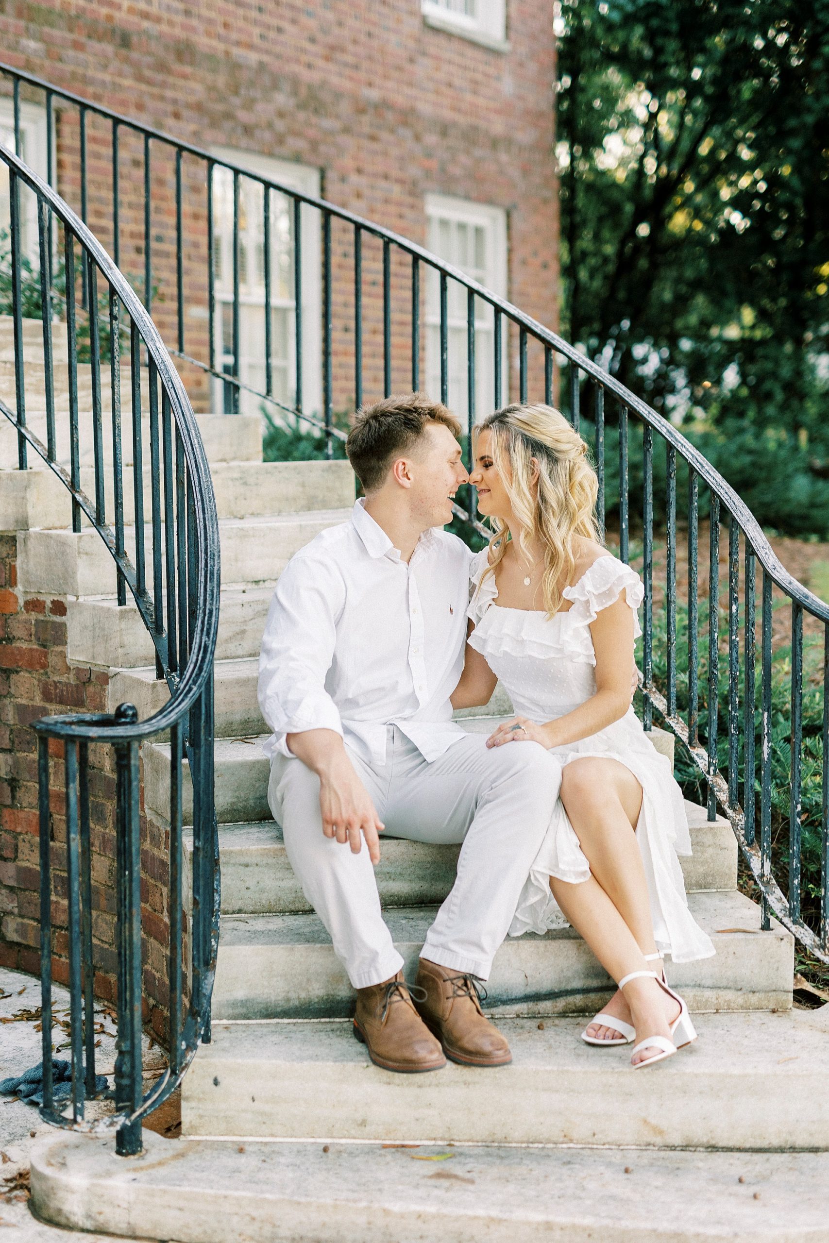 engaged couple sit on stone steps with iron railings