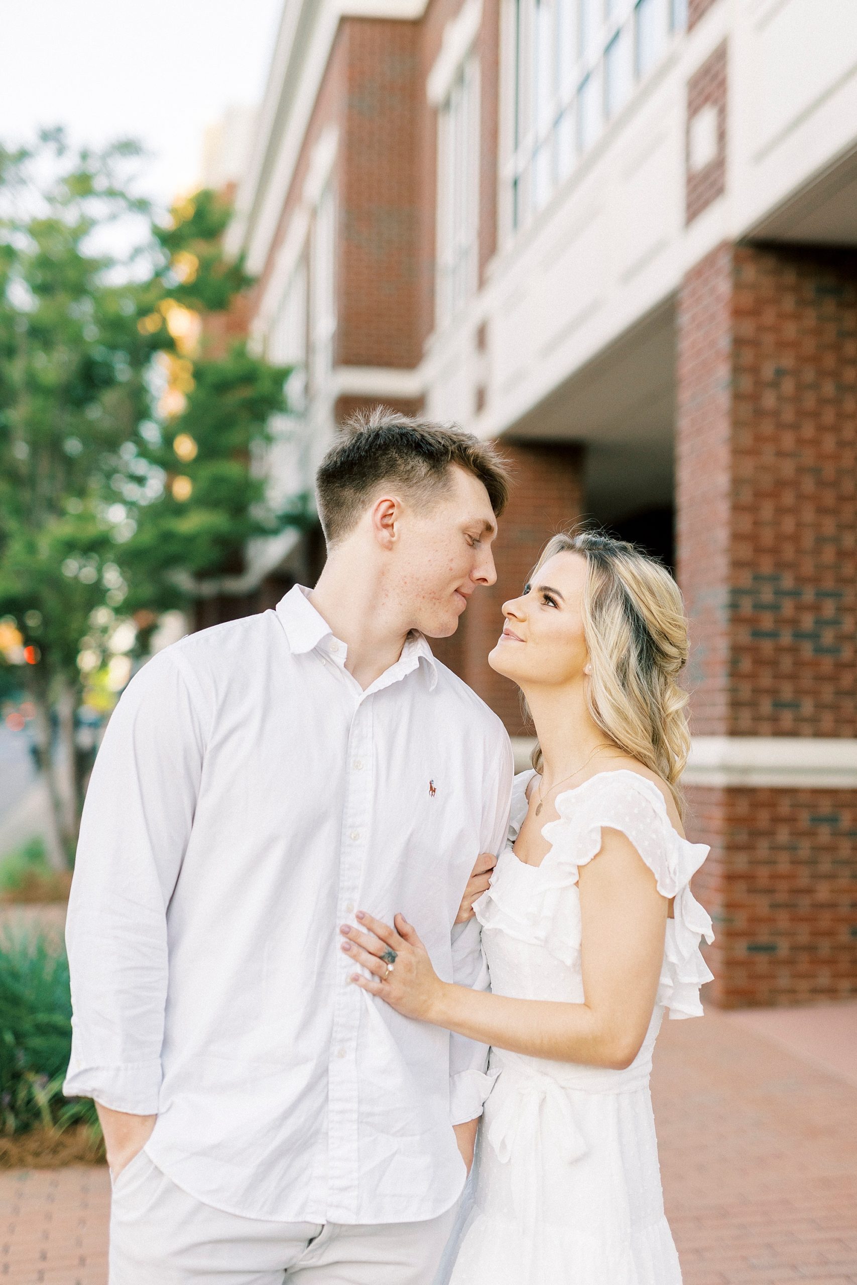 woman smiles up at fiancee during Downtown Concord engagement portraits