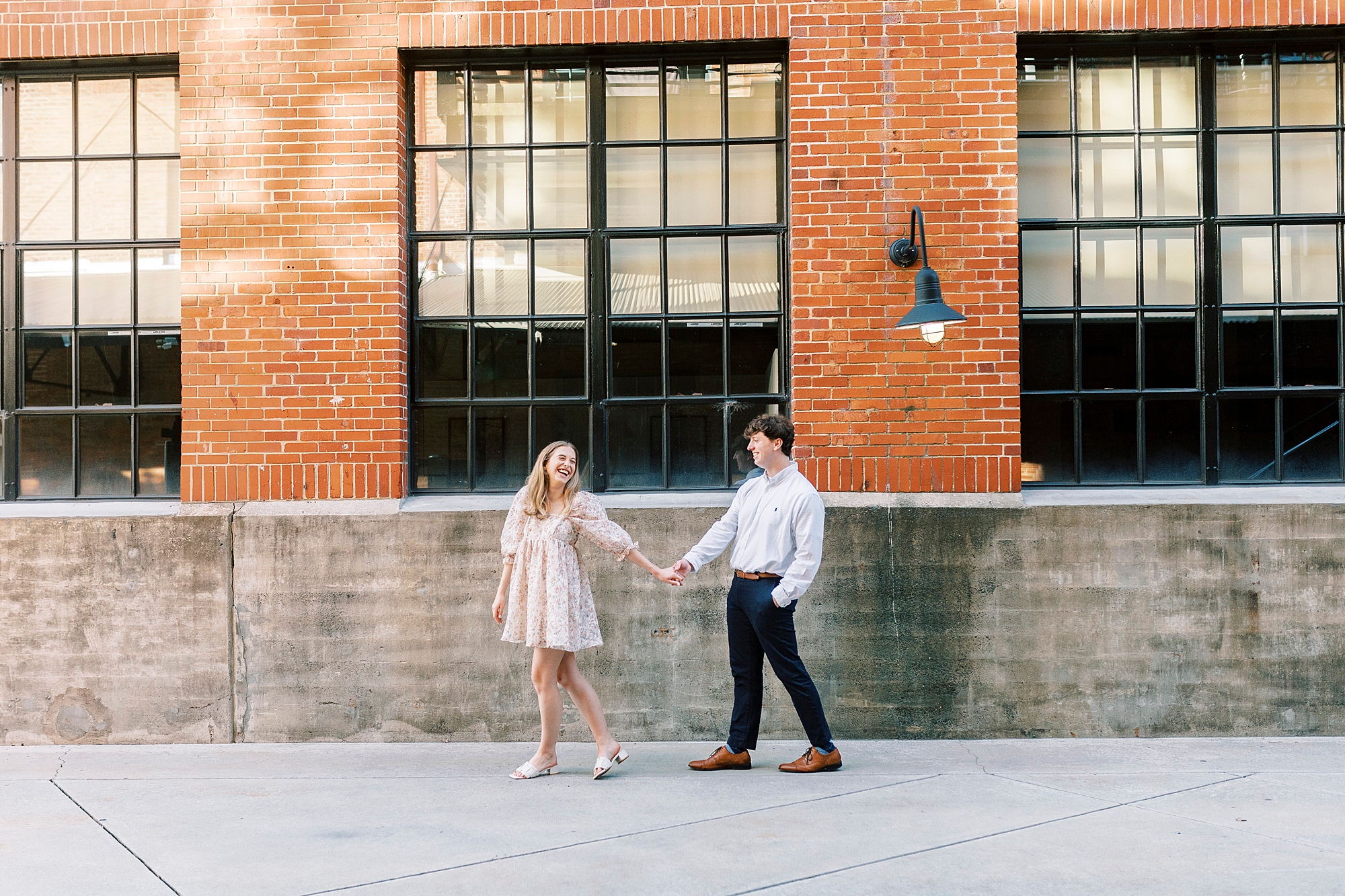 couple holds hands walking by warehouse at American Tobacco Campus