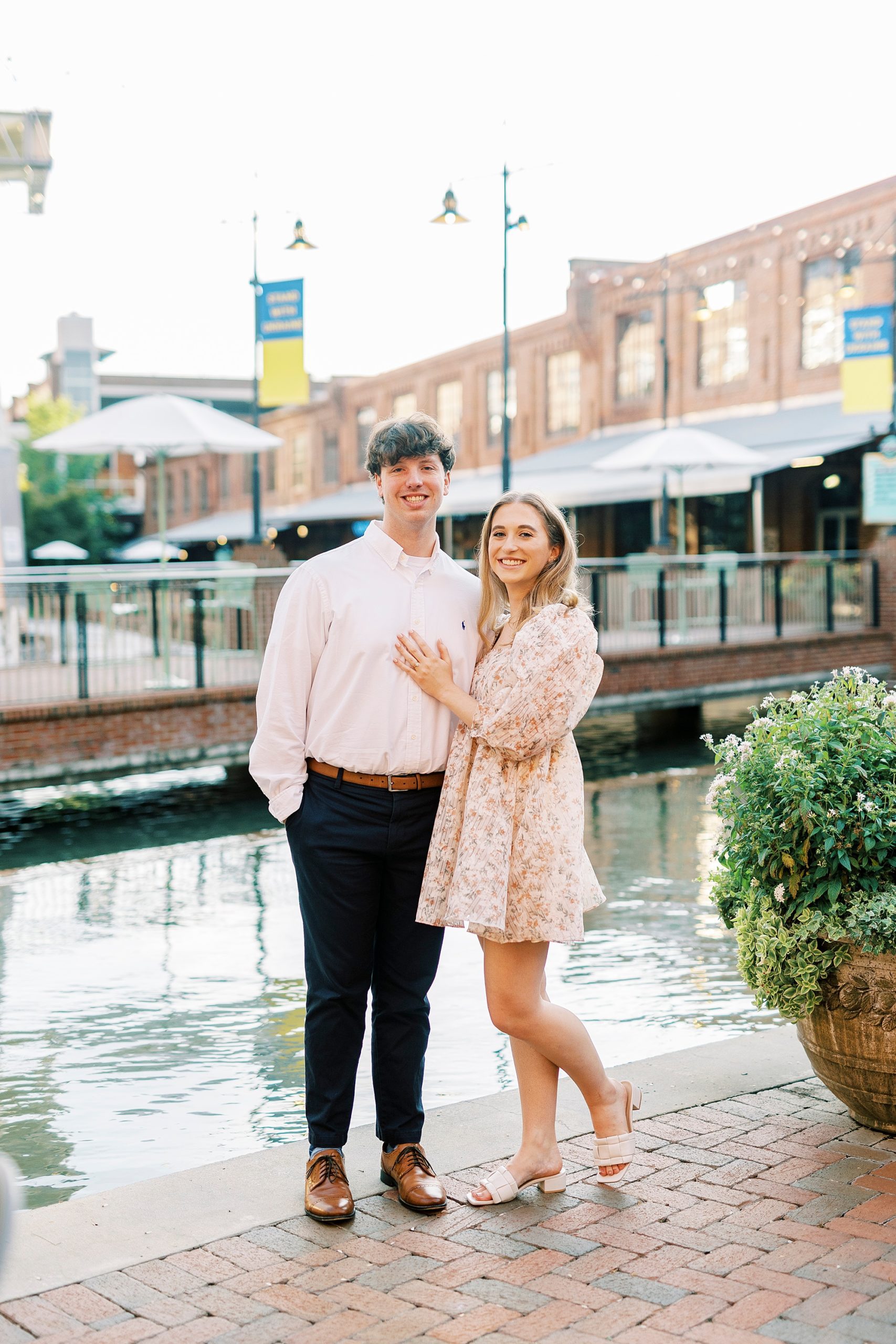 bride and groom pose by water outside the American Tobacco Campus