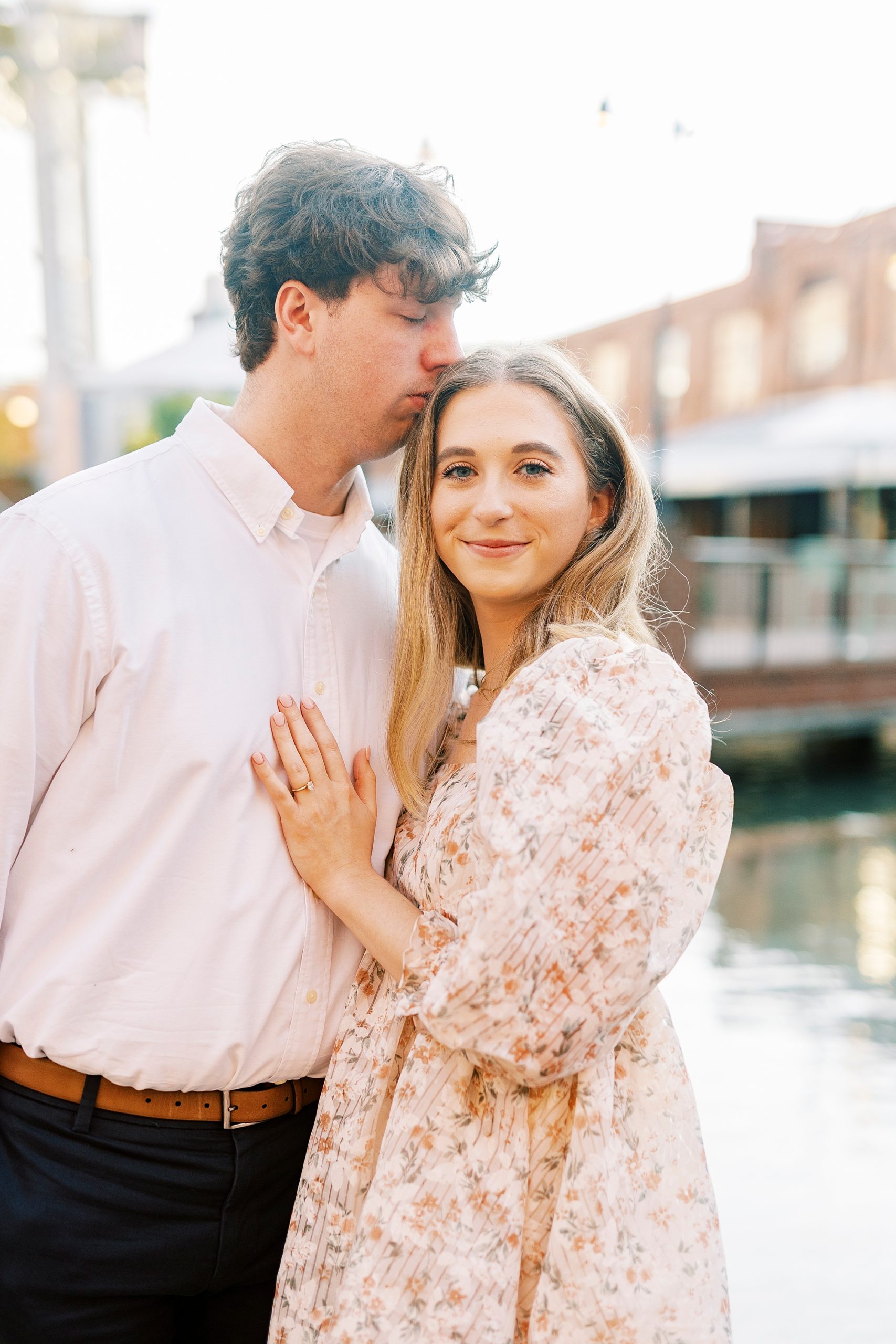 man kisses fiancee's head in Durham NC at American Tobacco Campus
