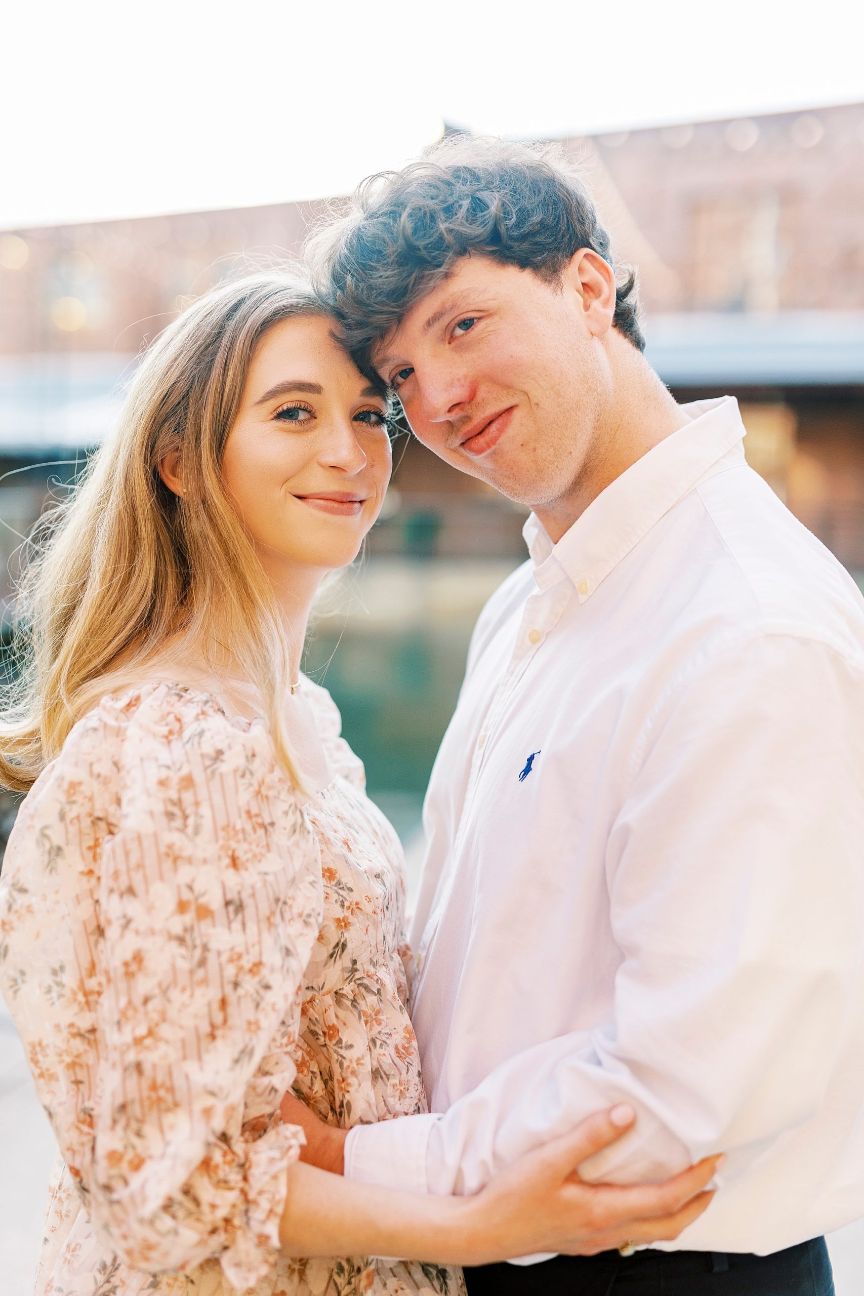 engaged couple leans heads together in Durham NC at the American Tobacco Campus