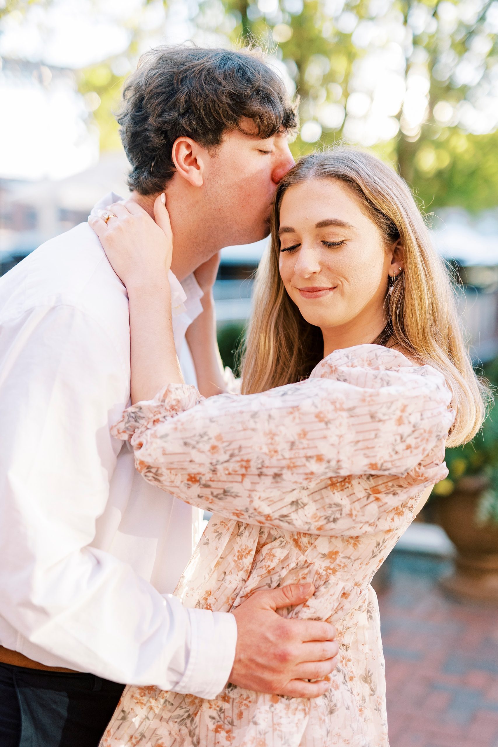 man kisses woman's forehead during sunset engagement session at American Tobacco Campus