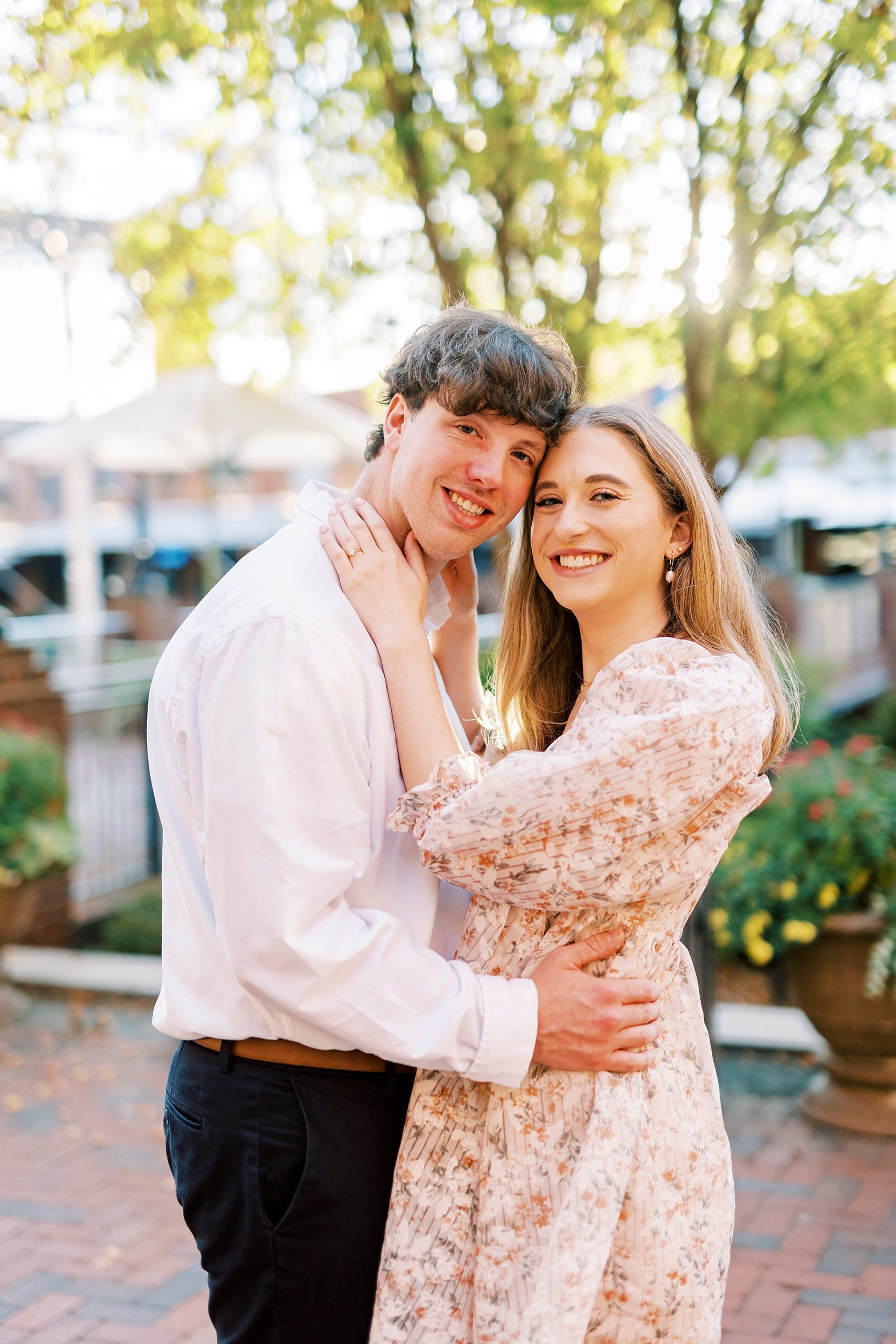 engaged couple leans heads together outside the American Tobacco Campus