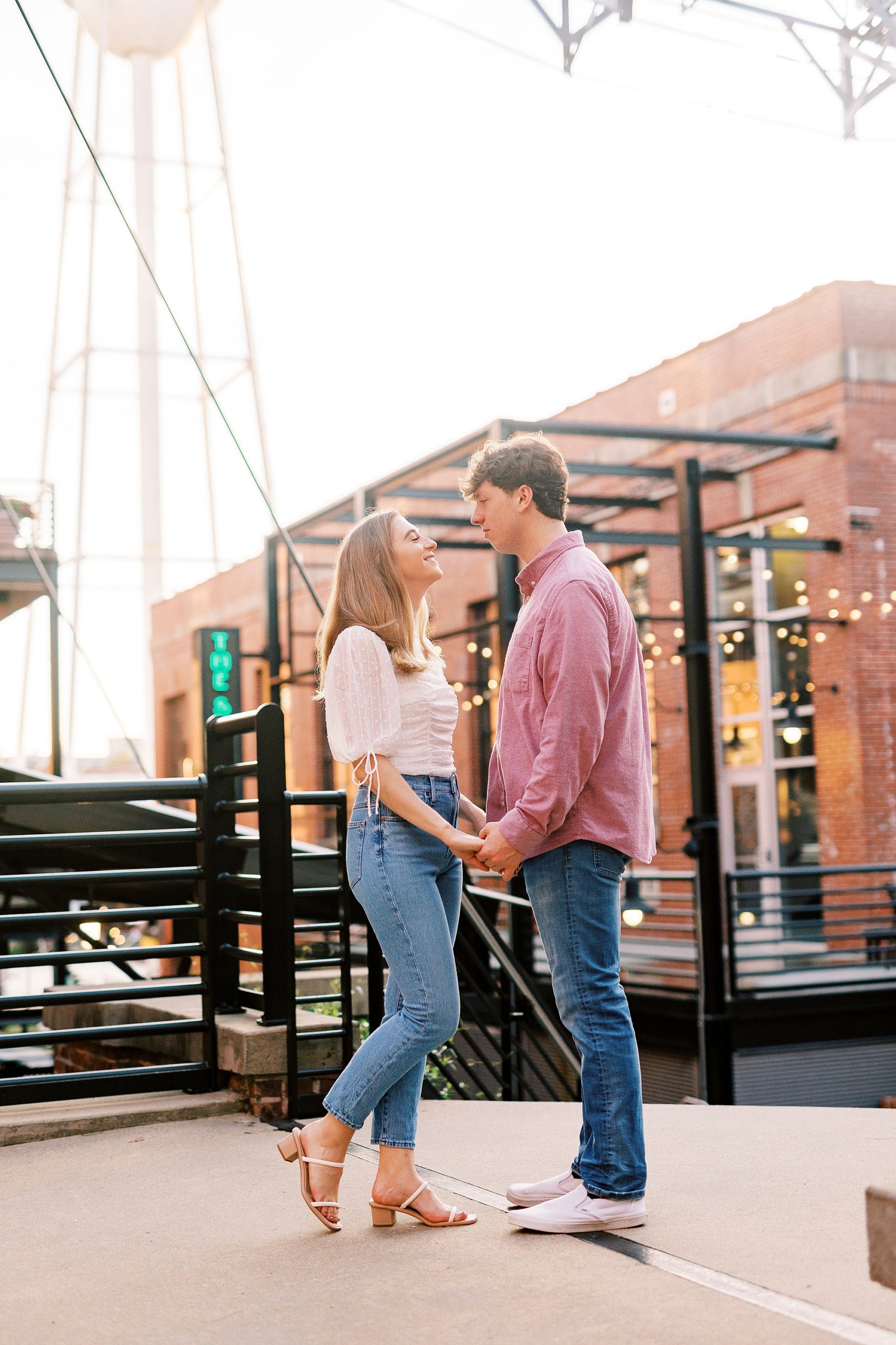 engaged couple holds hands smiling together outside the American Tobacco Campus