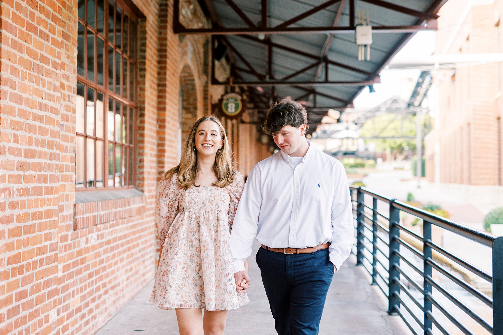 engaged couple holds hands walking outside the American Tobacco Campus