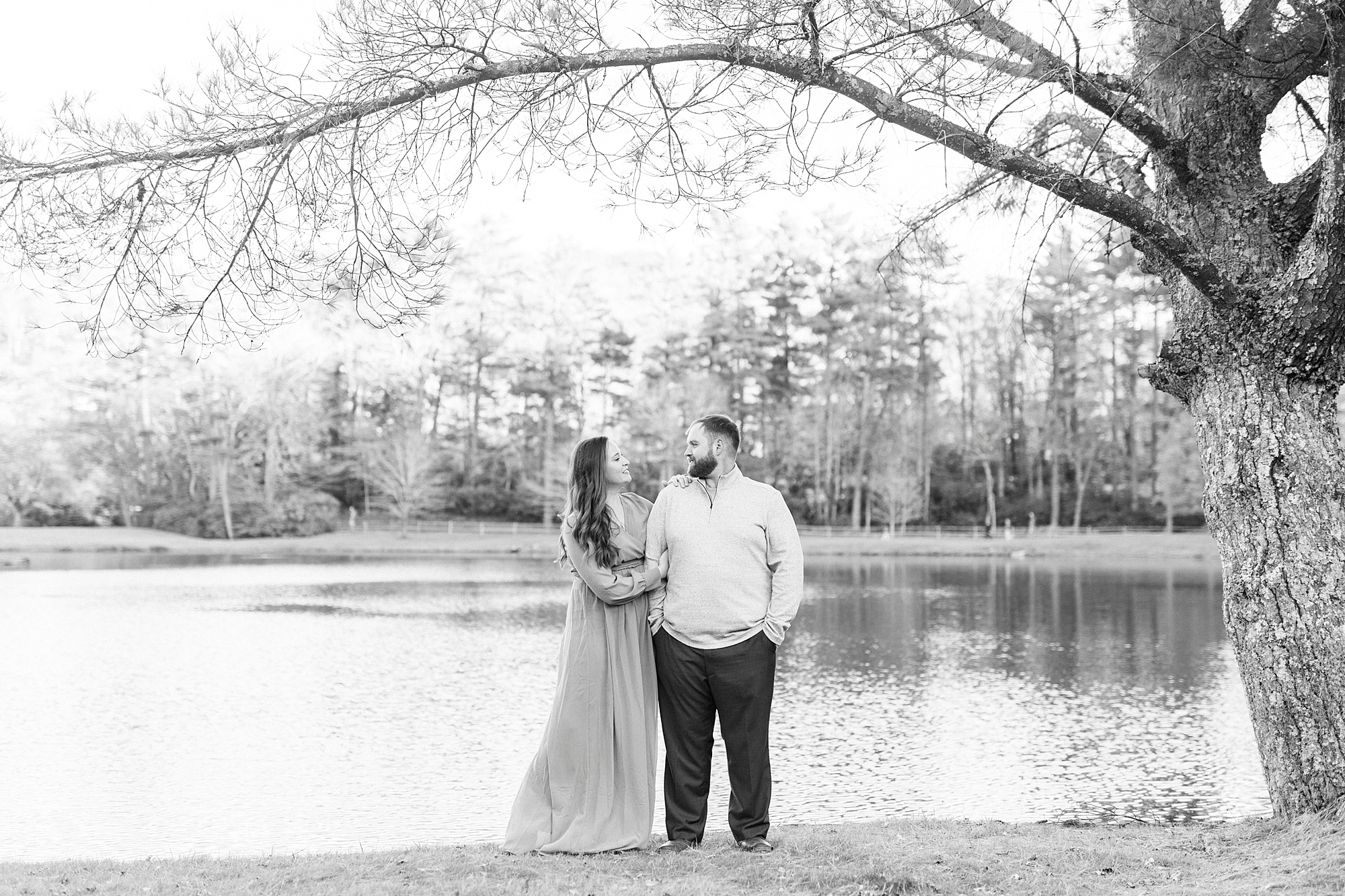 engaged couple stands together by lake at Chetola Resort