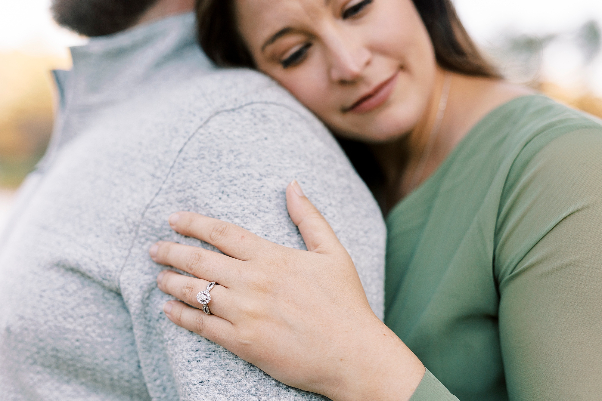 bride hugs groom from behind showing off her engagement ring on his arm